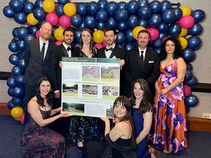 SLR team posing in front of balloons holding board for ACEC award winning project