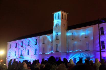 Ebrington Square light show on the Square's main building, with a crowd watching.