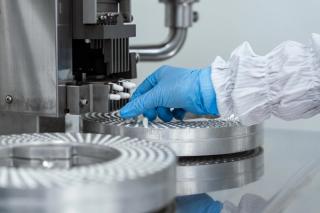 Modern laboratory or production equipment visible. Modern pharmaceutical manufacturing facility and laboratory setup with colorful supplement capsules and high-tech automated production equipment.