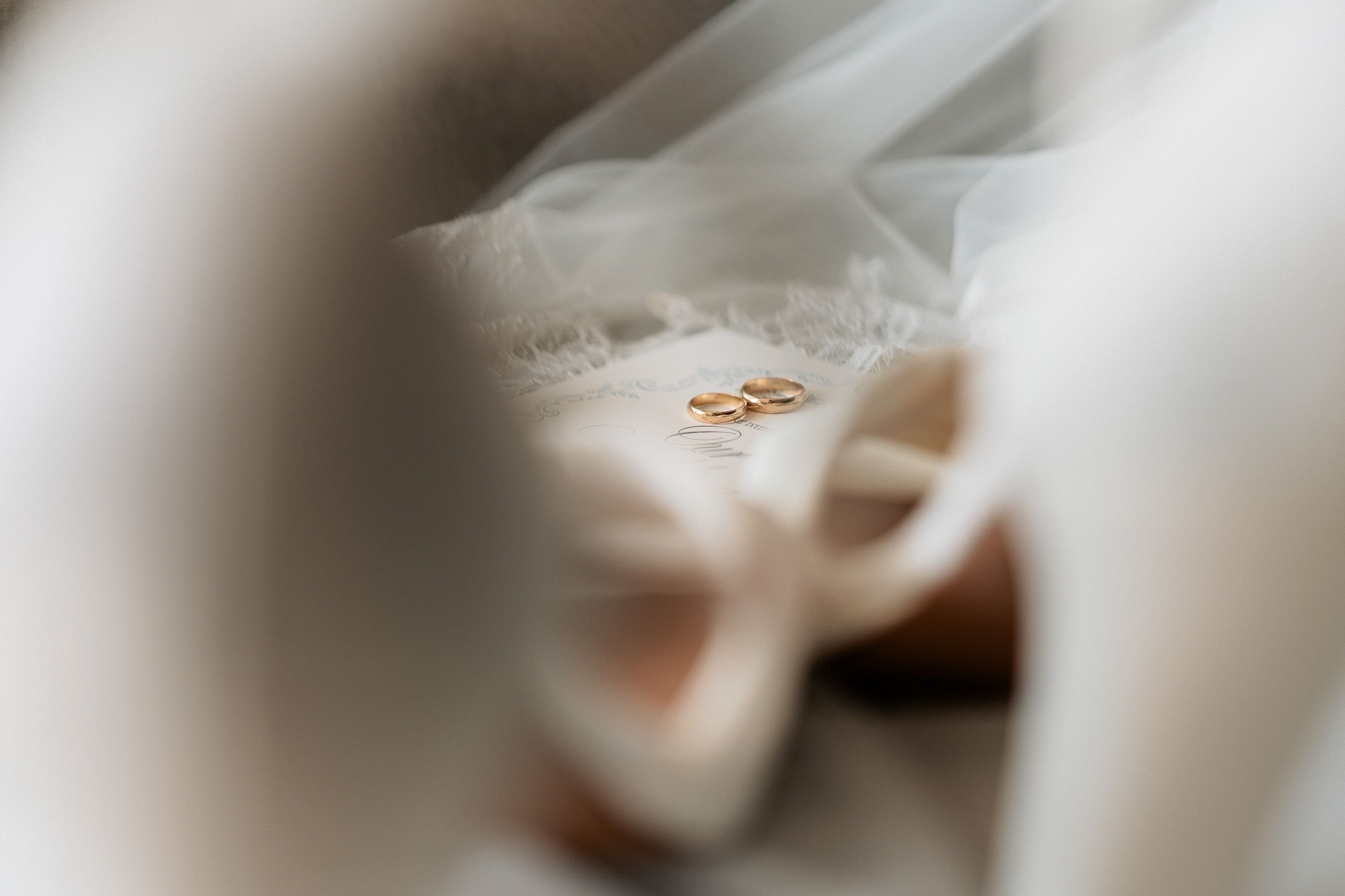 Gold wedding rings photographed with bridal shoes and veil before a wedding in Den Helder, Netherlands.