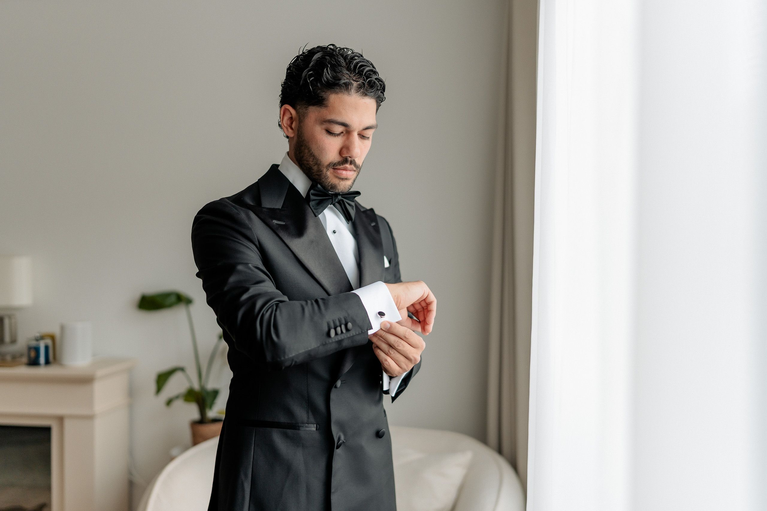 Groom adjusting his cufflinks while getting ready for his wedding in Den Helder, Netherlands.