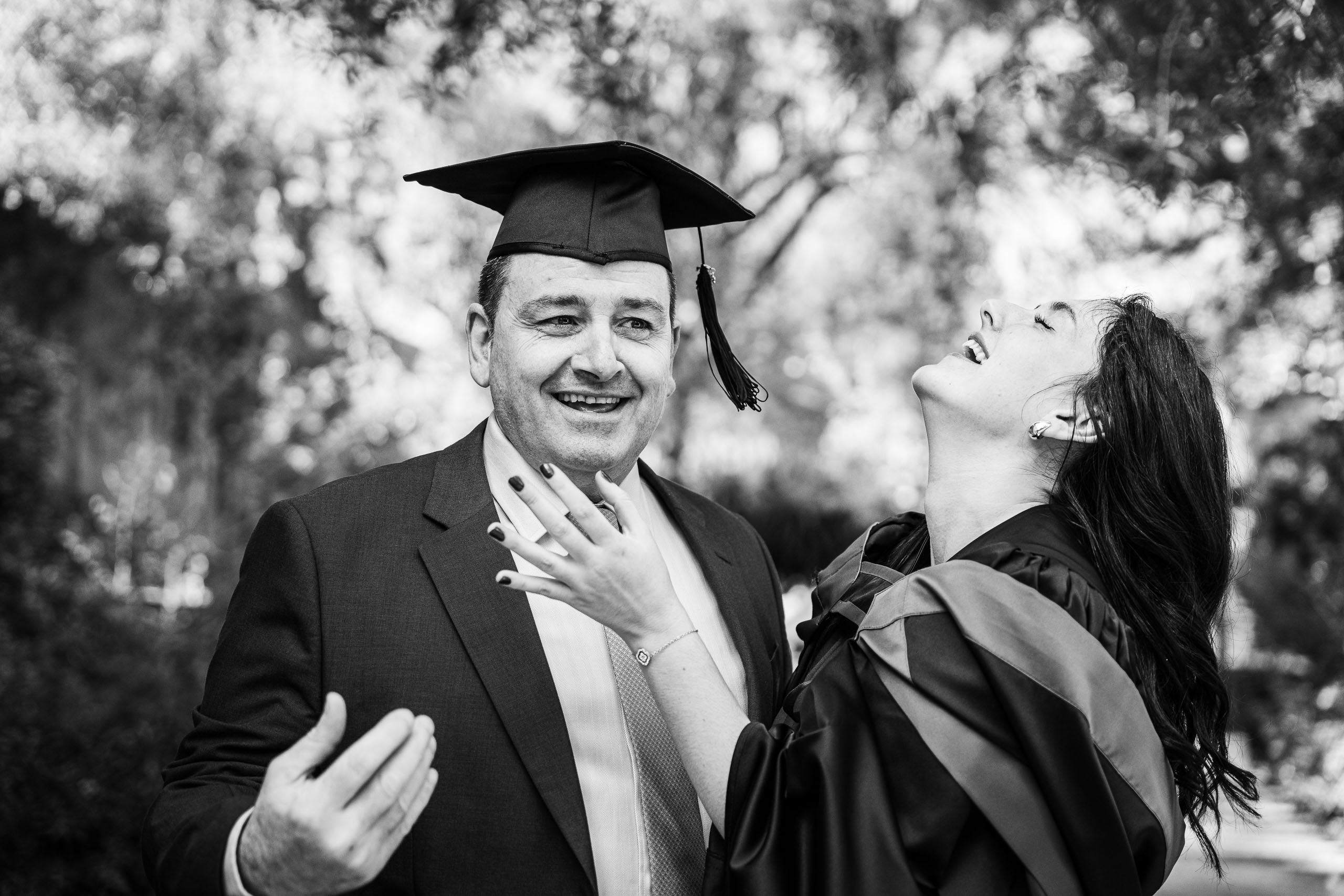 Black-and-white candid of a graduate laughing with her father during a graduation photoshoot in Malta.