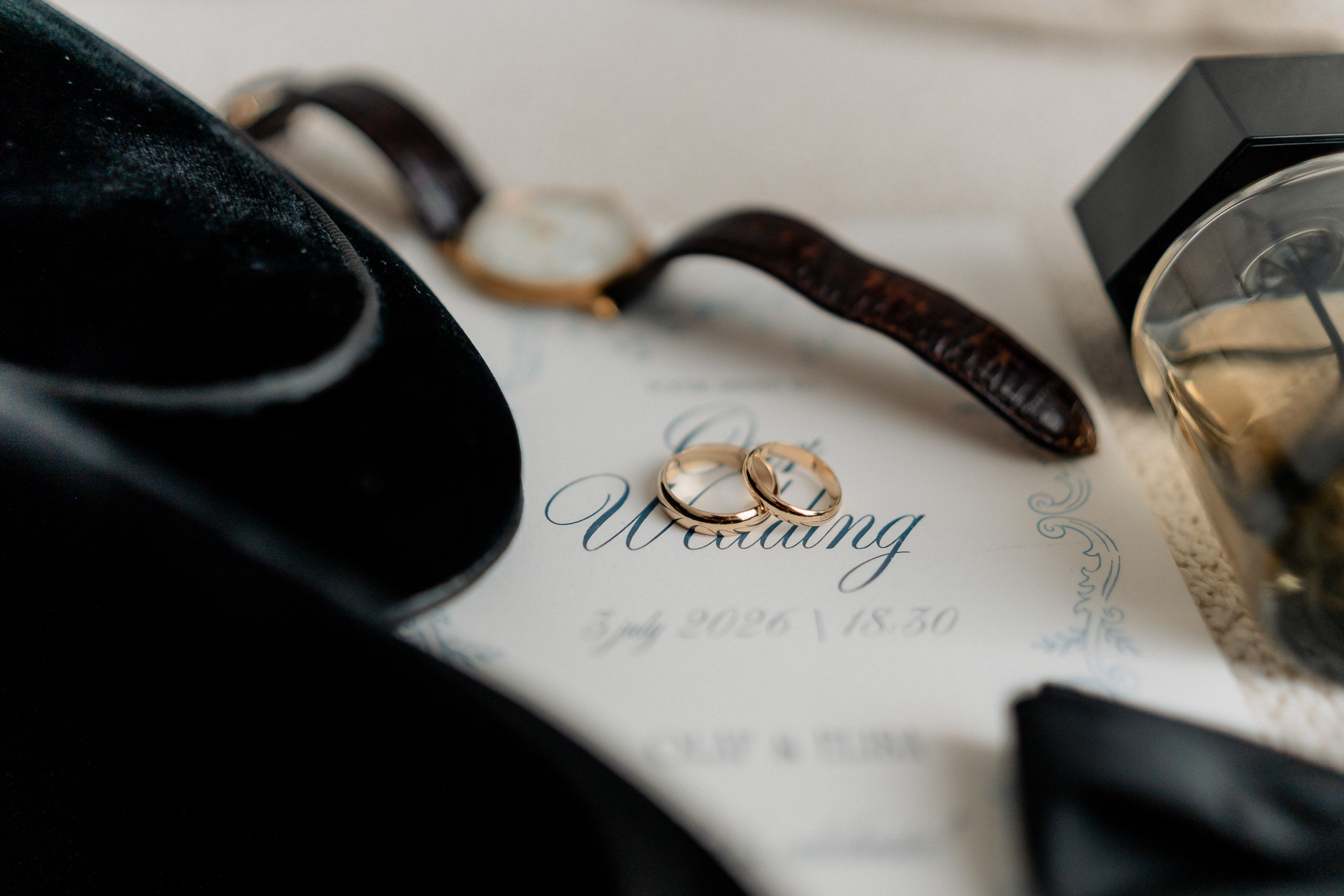 Wedding rings photographed with groom accessories and invitation before a wedding in Den Helder, Netherlands.