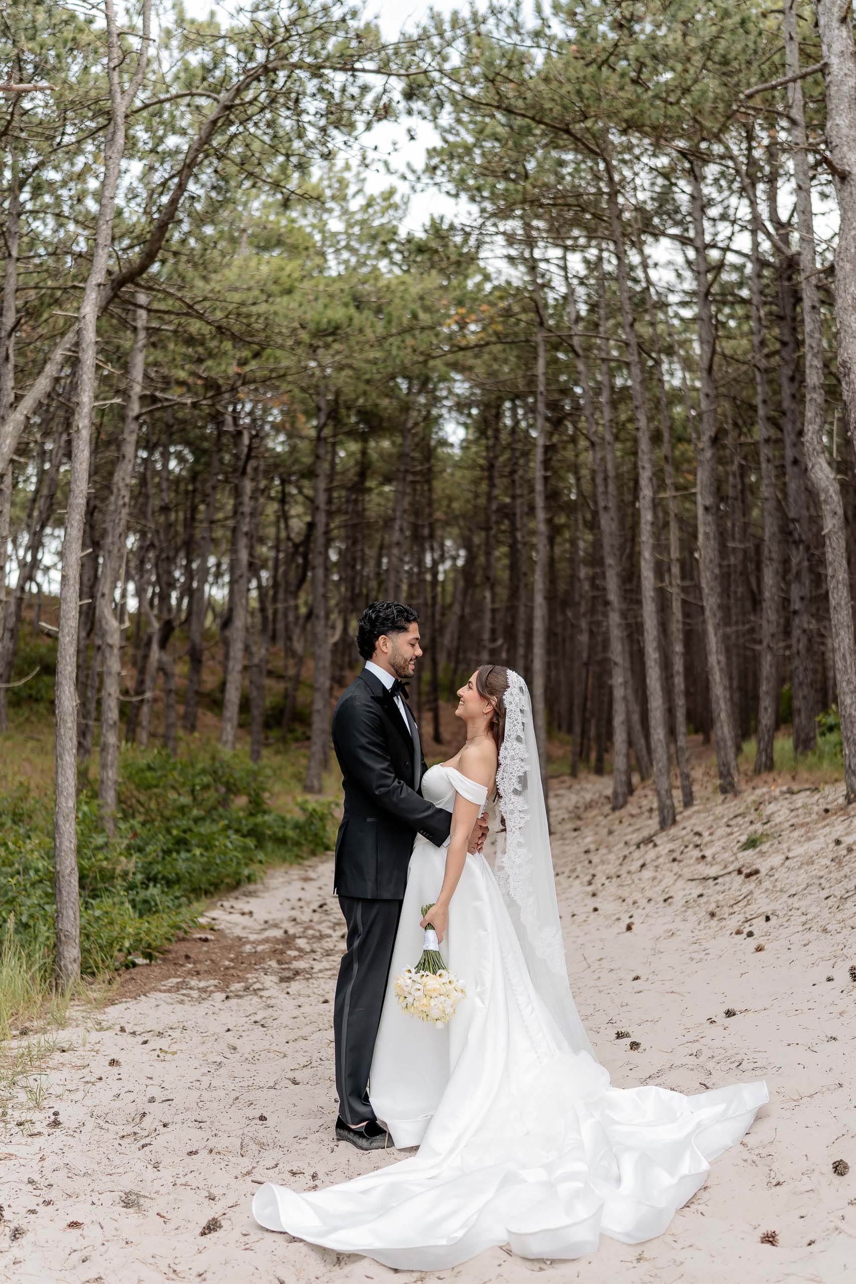 Bride and groom standing together among the pine trees at Schoorlse Duinen in the Netherlands.