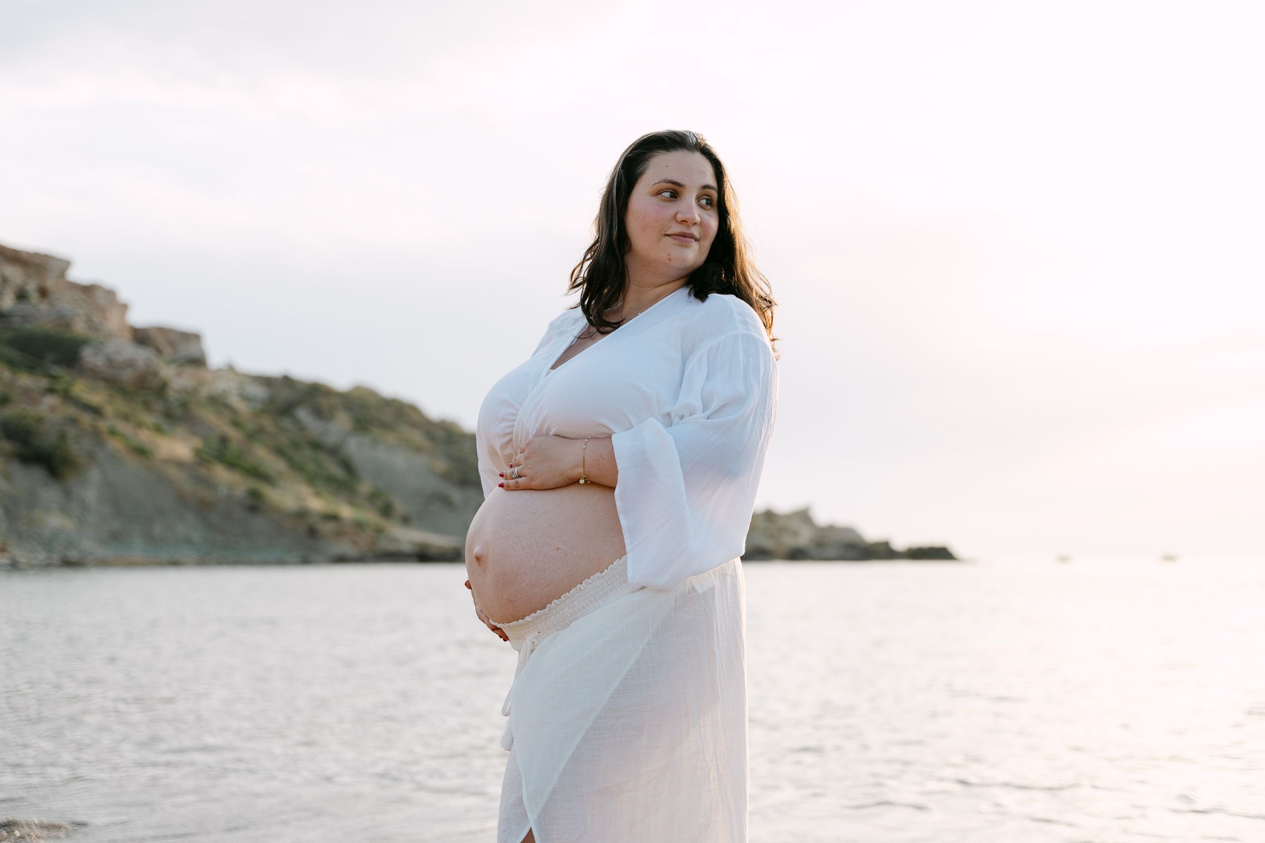 Pregnant woman posing at Riviera Bay during a maternity photoshoot in Malta
