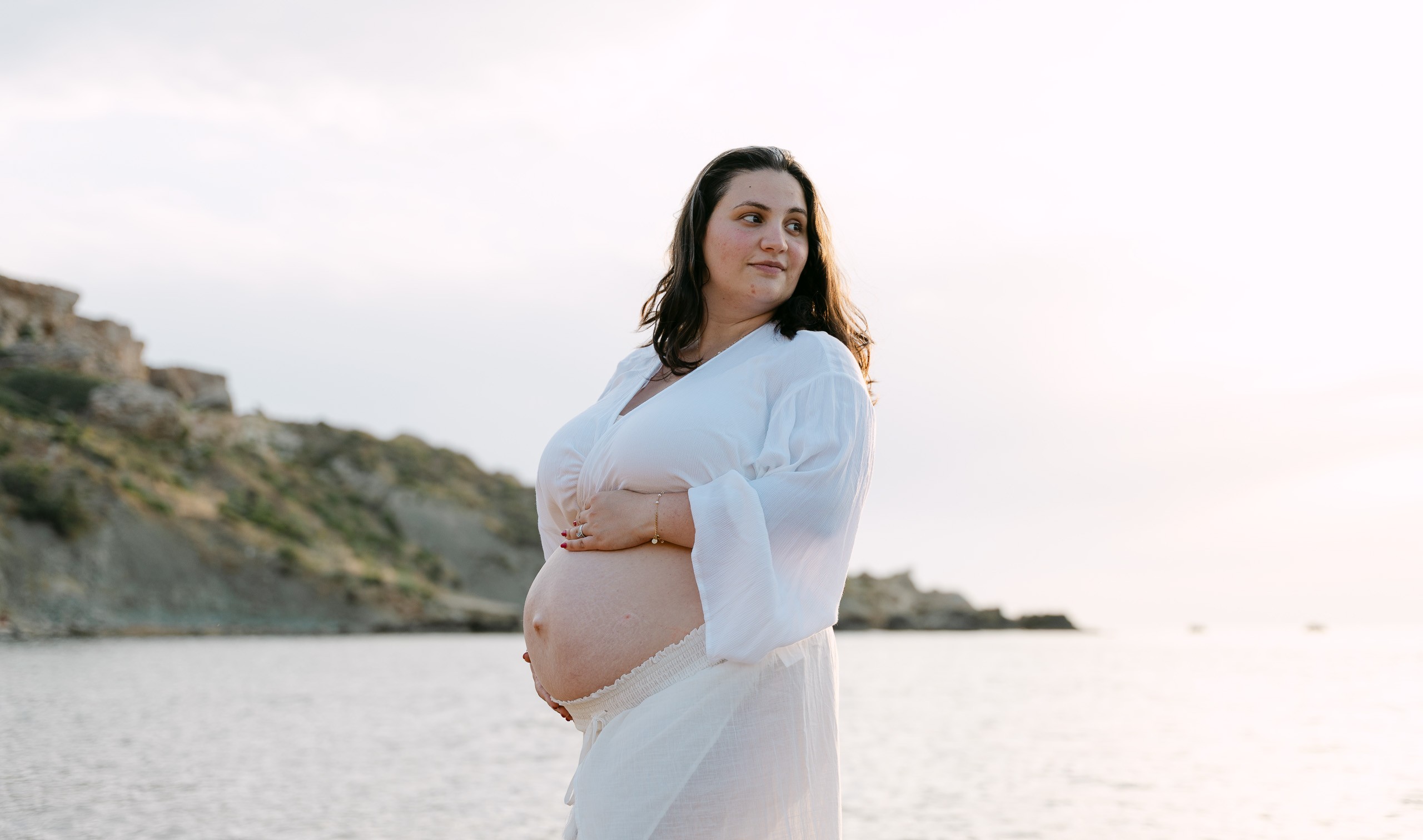 Pregnant woman posing at Riviera Bay during a maternity photoshoot in Malta