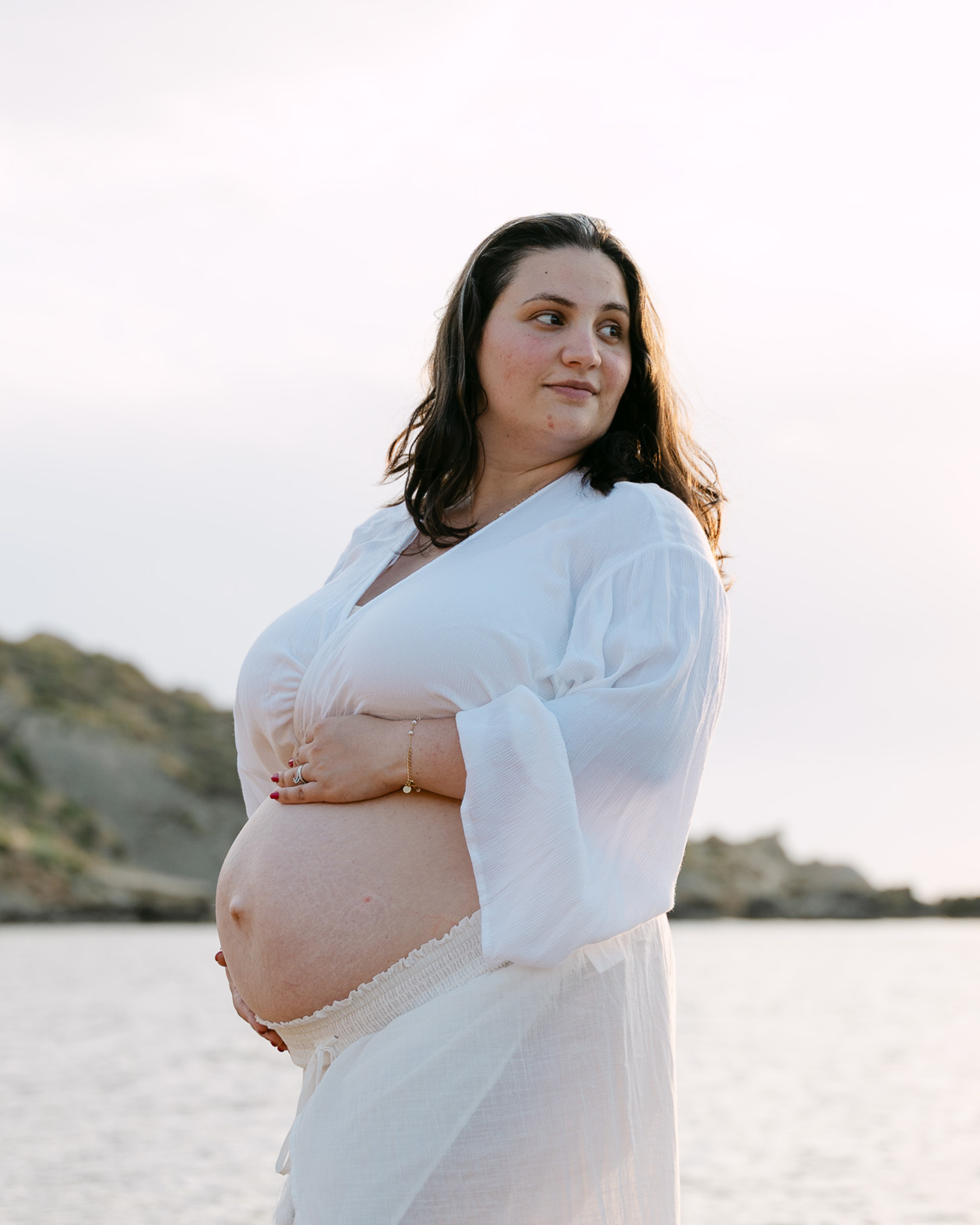 Pregnant woman posing at Riviera Bay during a maternity photoshoot in Malta