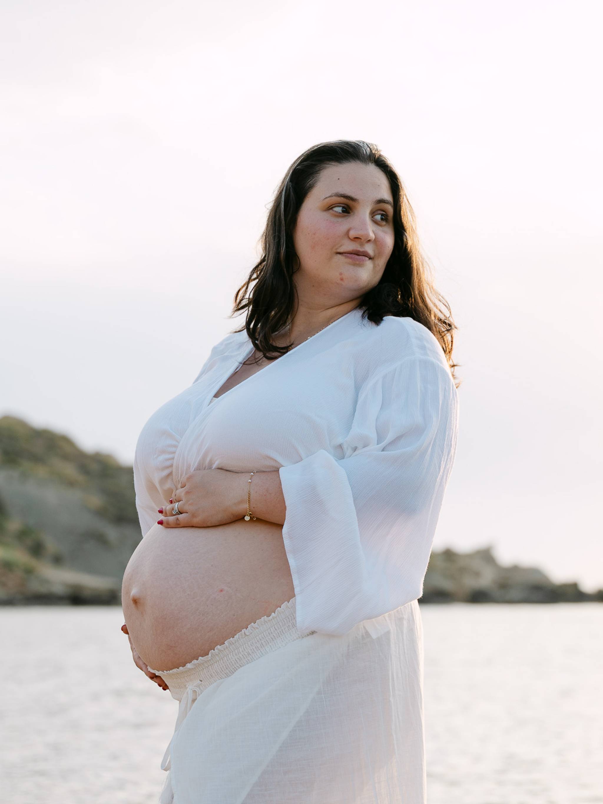 Pregnant woman posing at Riviera Bay during a maternity photoshoot in Malta