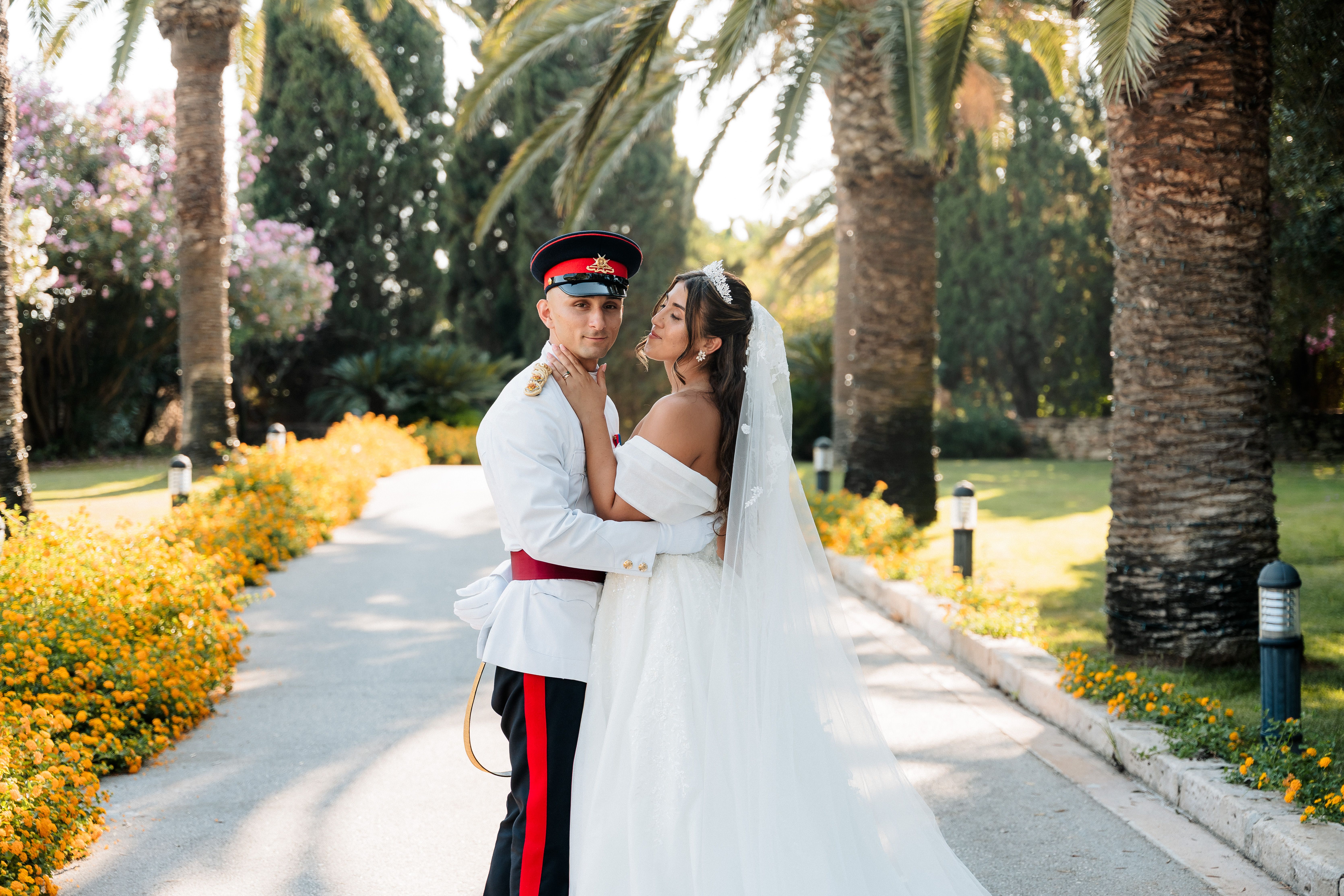 Bride and groom posing together in the palm-lined gardens of Ir-Razzett L-Abjad during their wedding in Malta.
