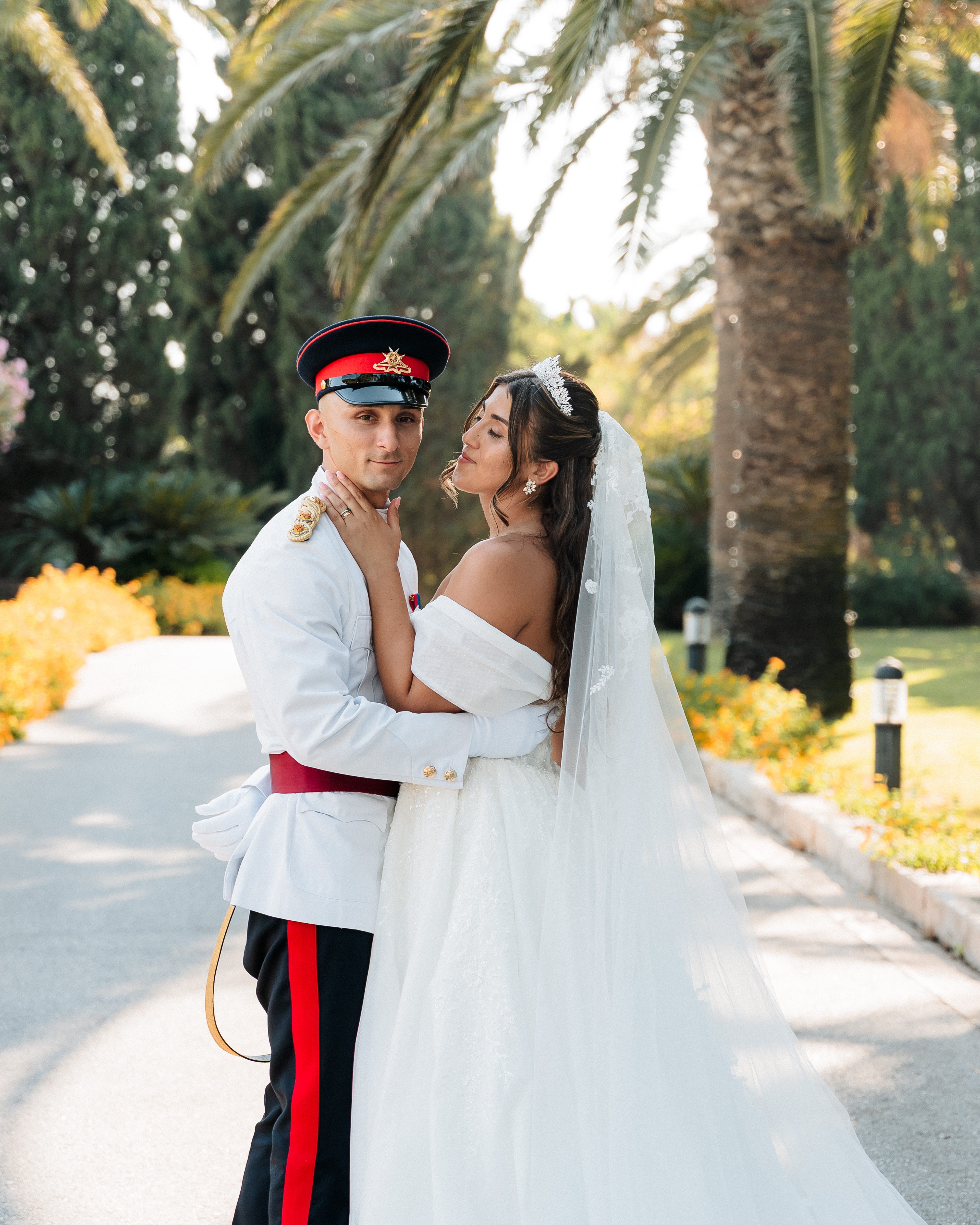 Bride and groom posing together in the palm-lined gardens of Ir-Razzett L-Abjad during their wedding in Malta.