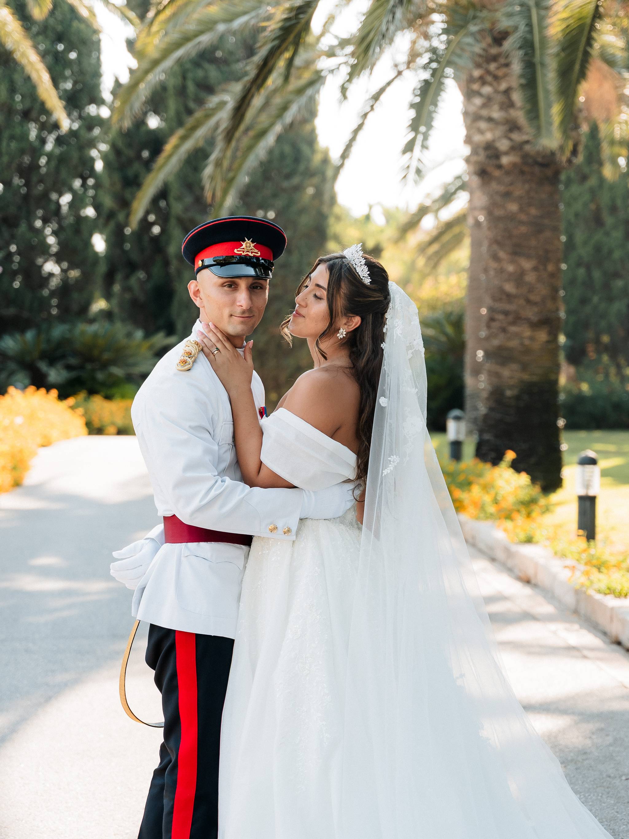 Bride and groom posing together in the palm-lined gardens of Ir-Razzett L-Abjad during their wedding in Malta.
