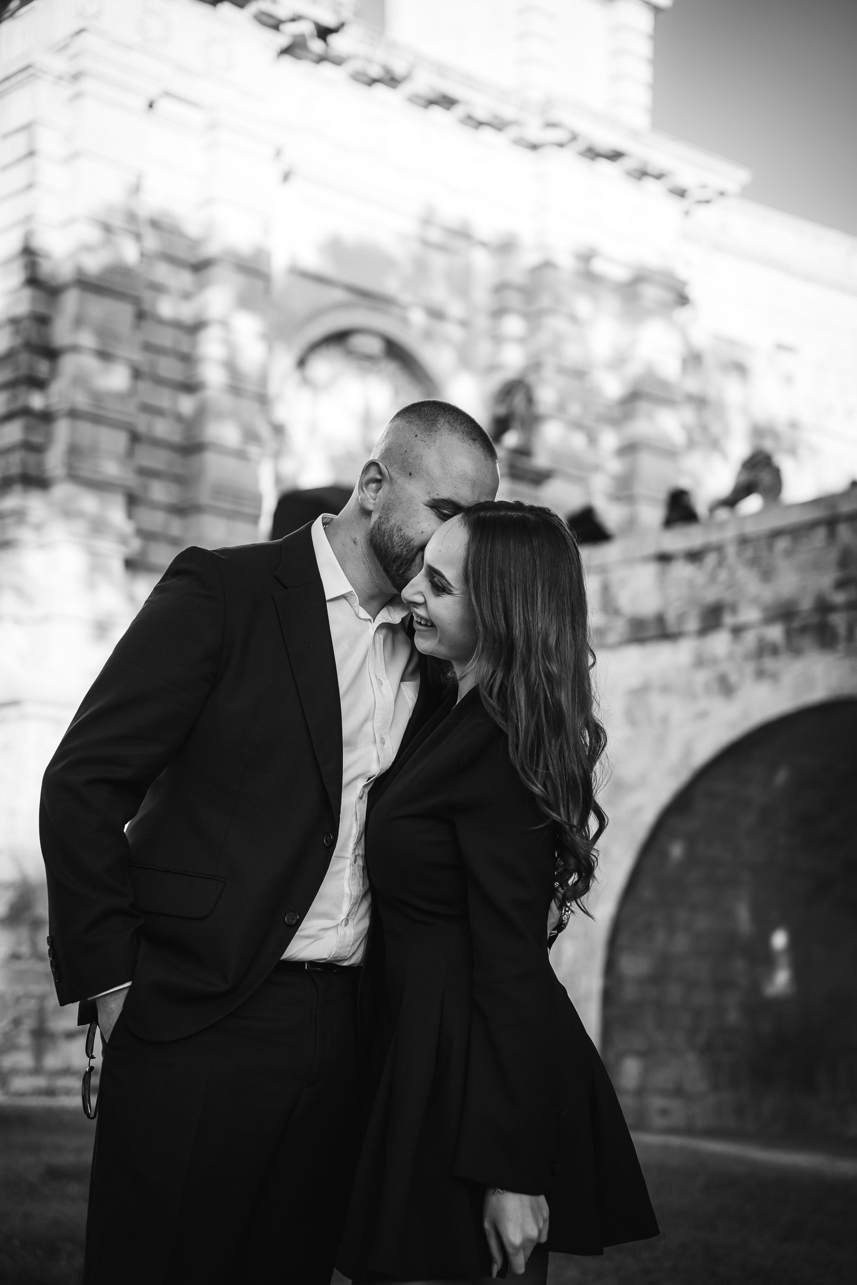 Black-and-white portrait of a graduate laughing with her partner in front of Mdina Gate in Malta.