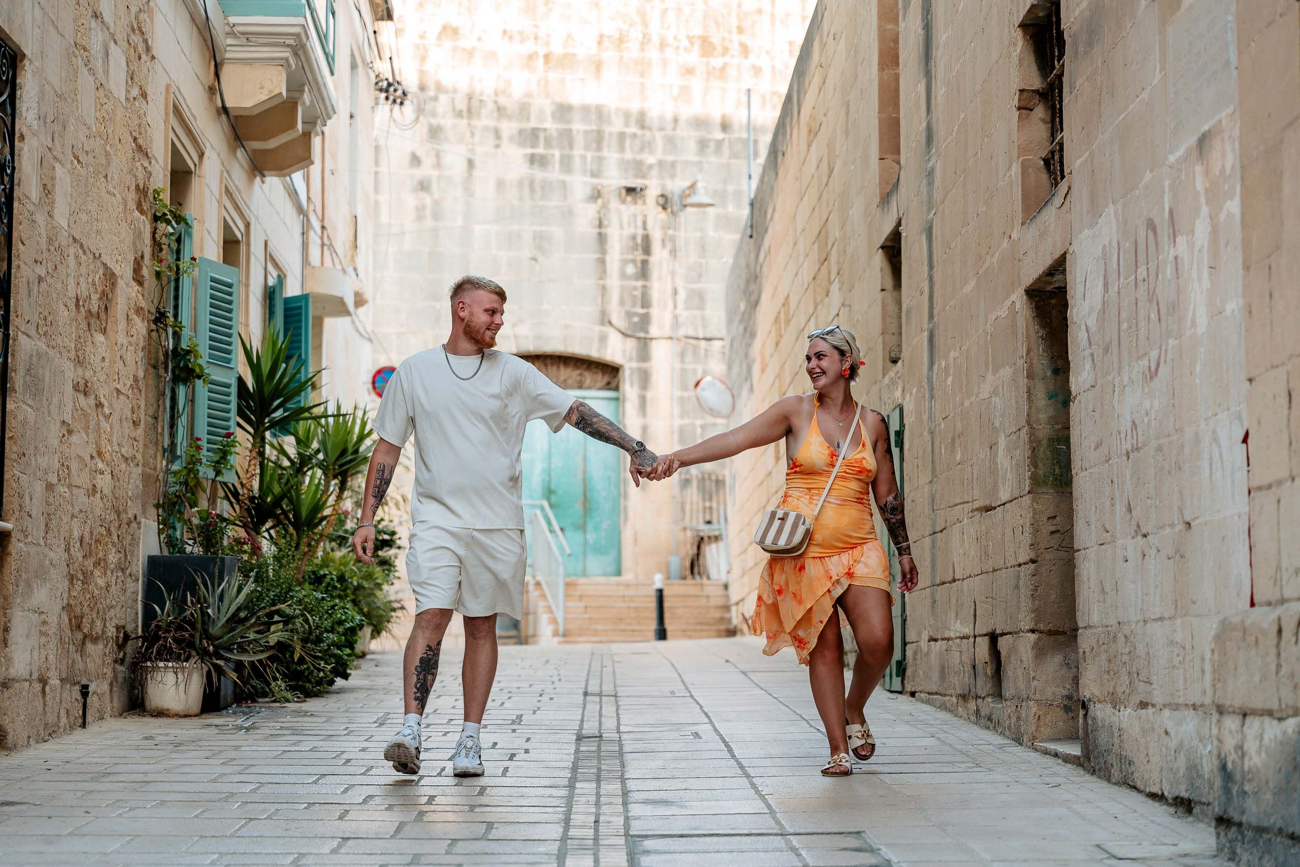 Newly engaged couple walking through the historic streets of Birgu, Malta