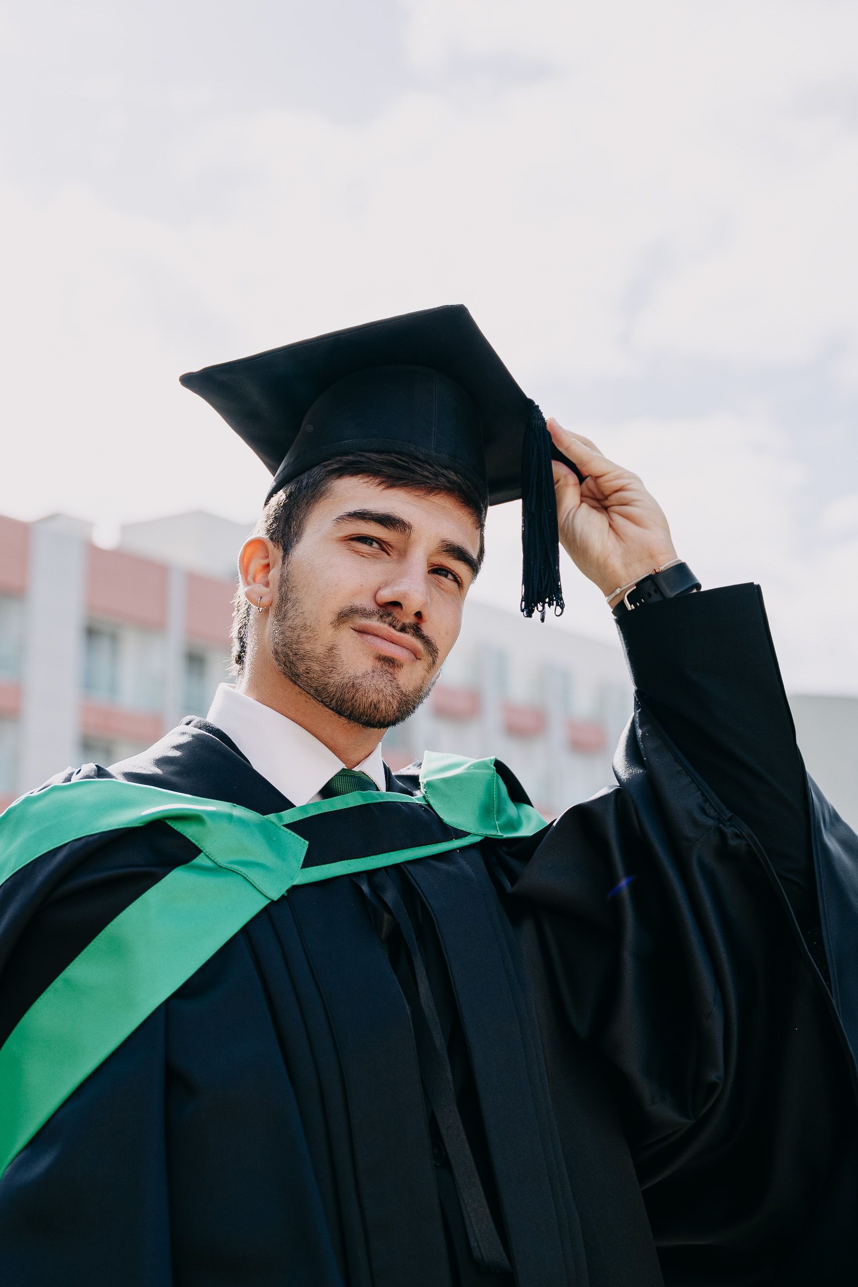 Close-up portrait of a male graduate adjusting his cap during a photoshoot at Hilton Malta.