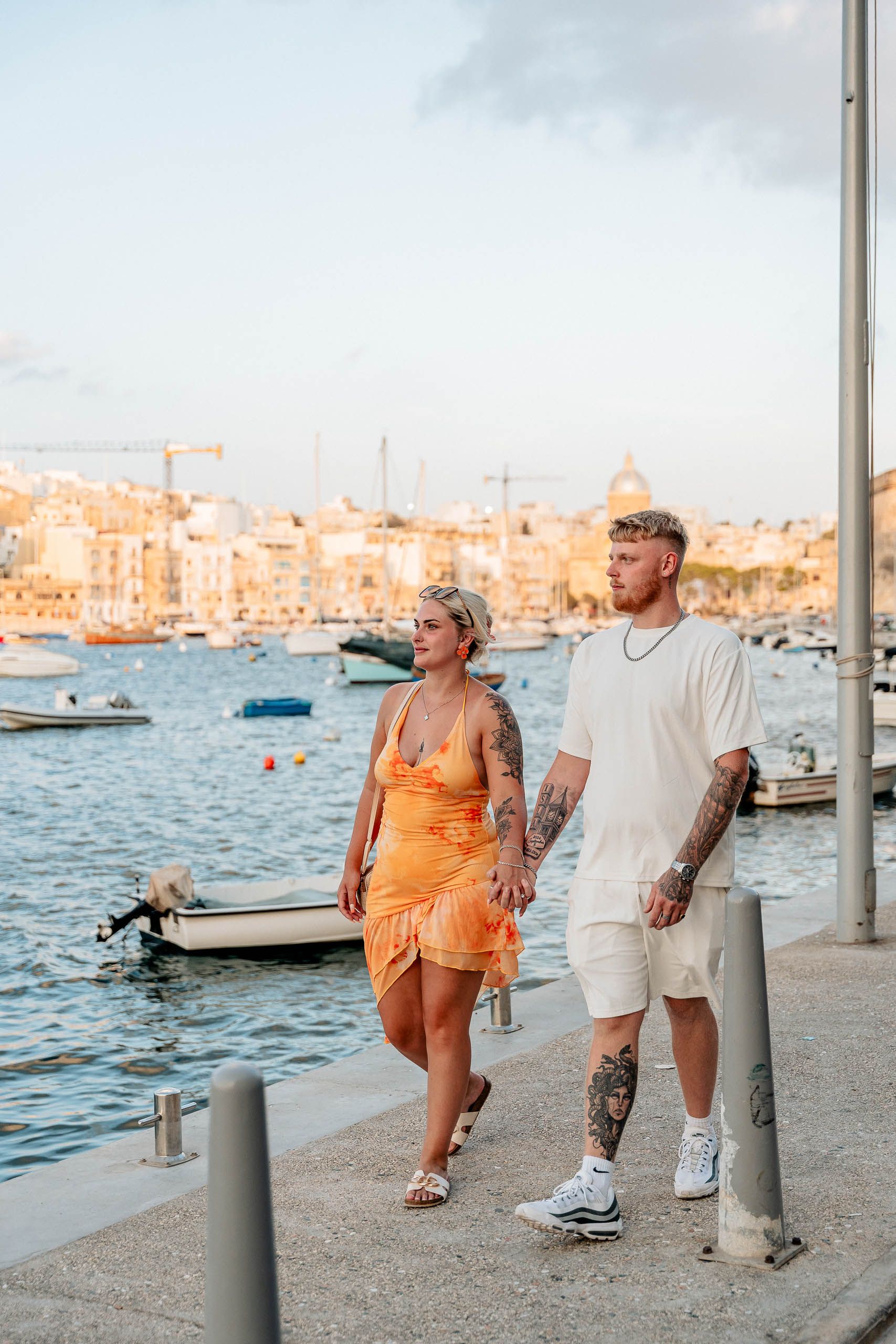 Engaged couple walking along the Birgu waterfront after a surprise proposal in Malta