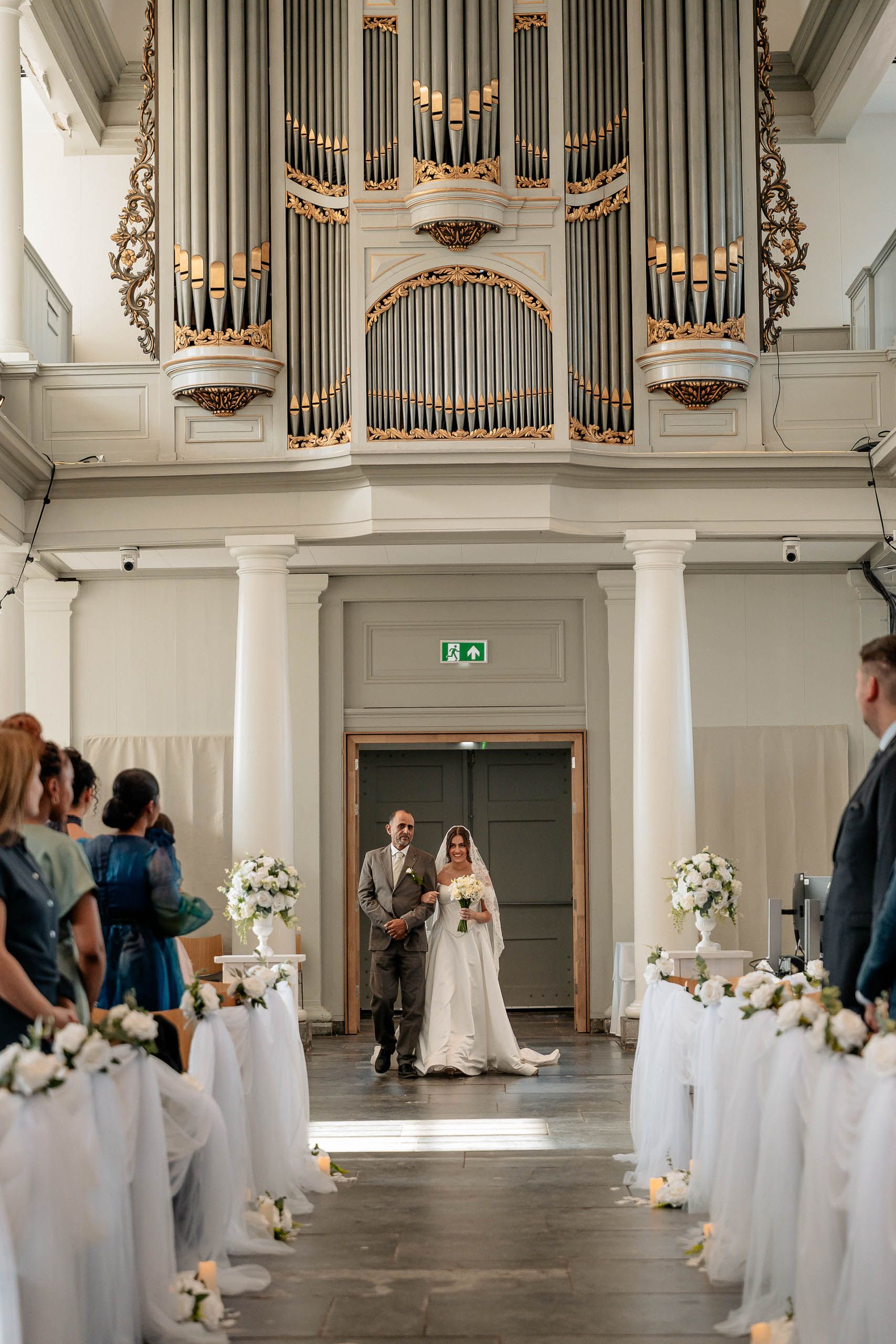 Bride walking down the aisle with her father during a church wedding ceremony in Den Helder, Netherlands.