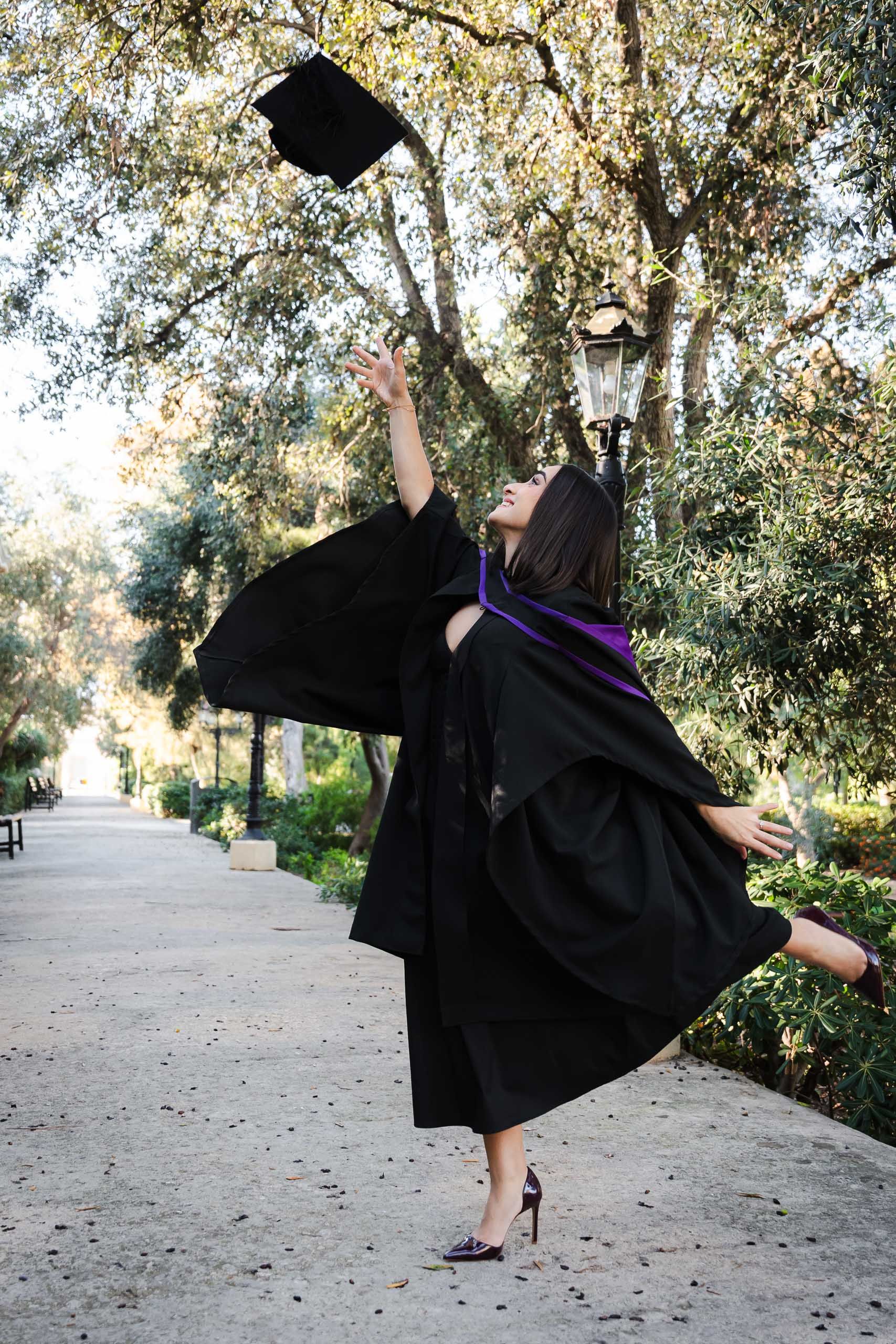 Graduate tossing her cap in the air while celebrating at Romeo Romano Gardens in Malta.