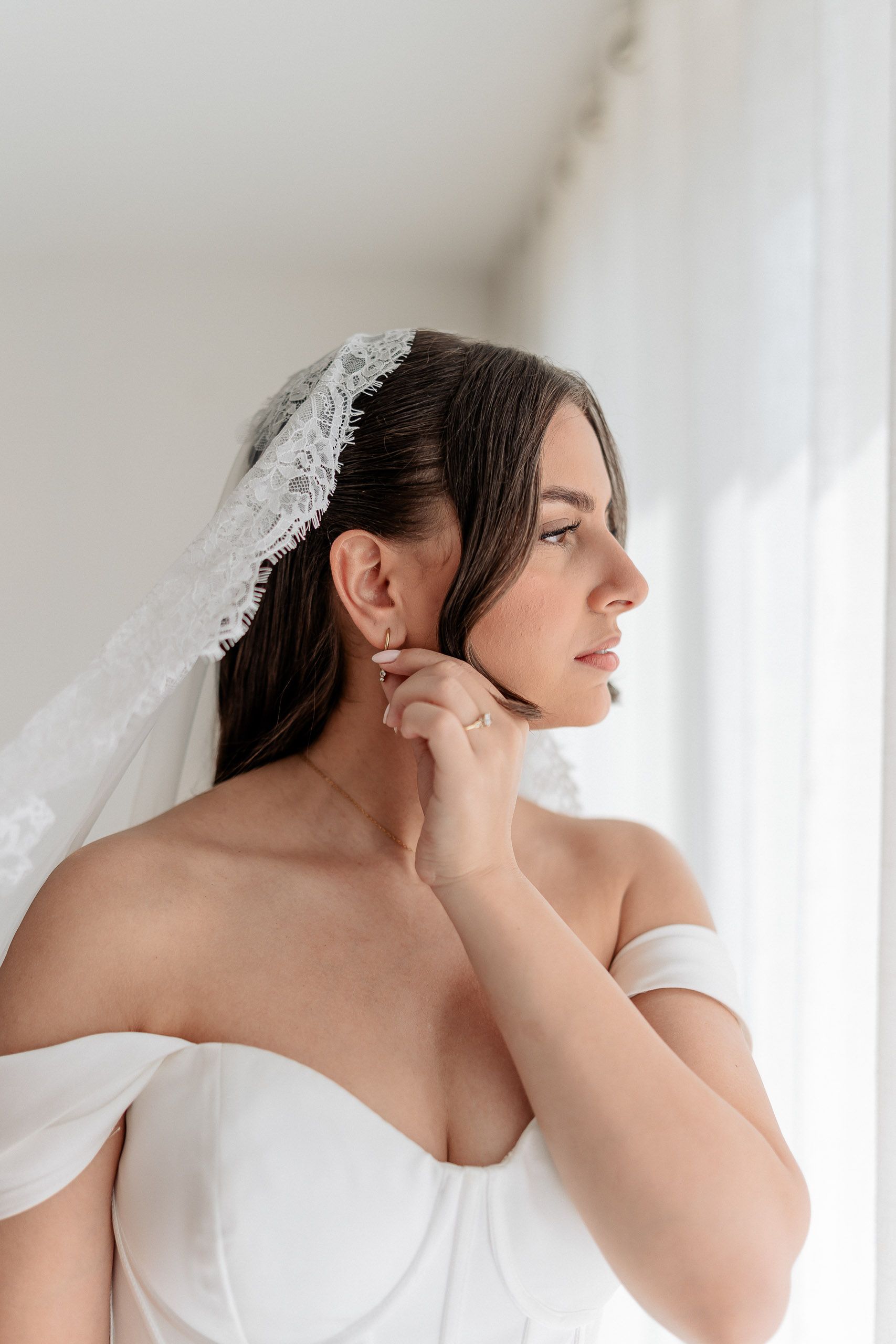 Bride adjusting her earring while getting ready for her wedding in Den Helder, Netherlands.