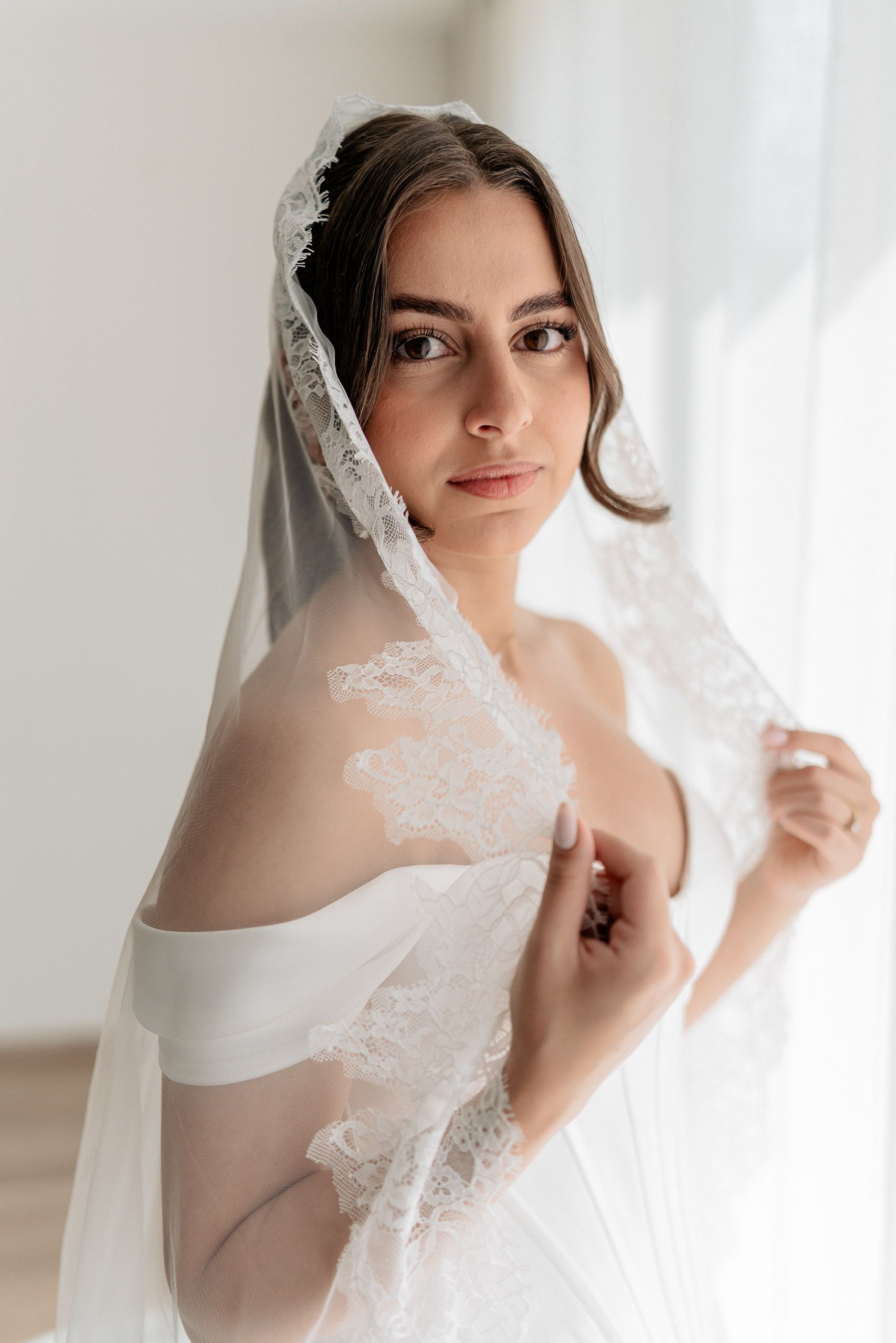 Close-up bridal portrait with lace veil during wedding preparations in Den Helder, Netherlands.