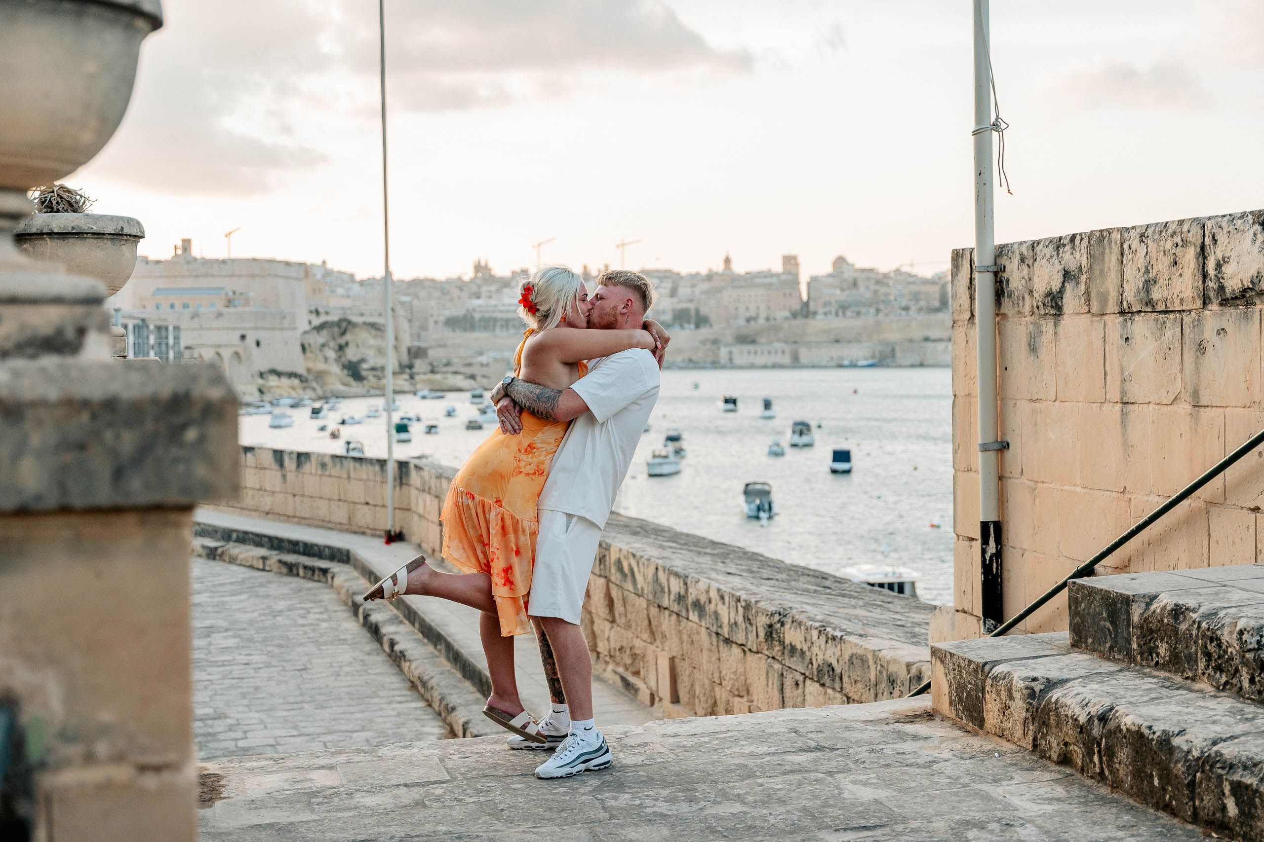 Engaged couple kissing overlooking Grand Harbour after a proposal in Birgu, Malta