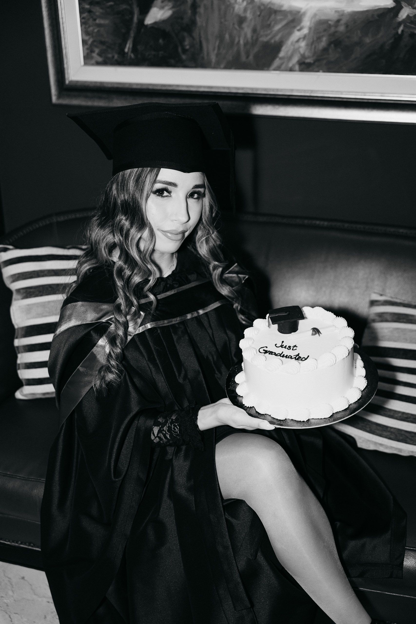 Black-and-white portrait of a graduate holding a celebration cake at Corinthia Palace Malta