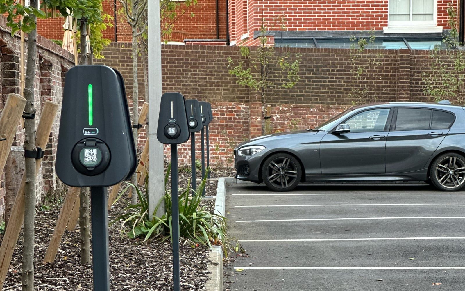 A row of post-mounted Brim chargers along the bays of a car park