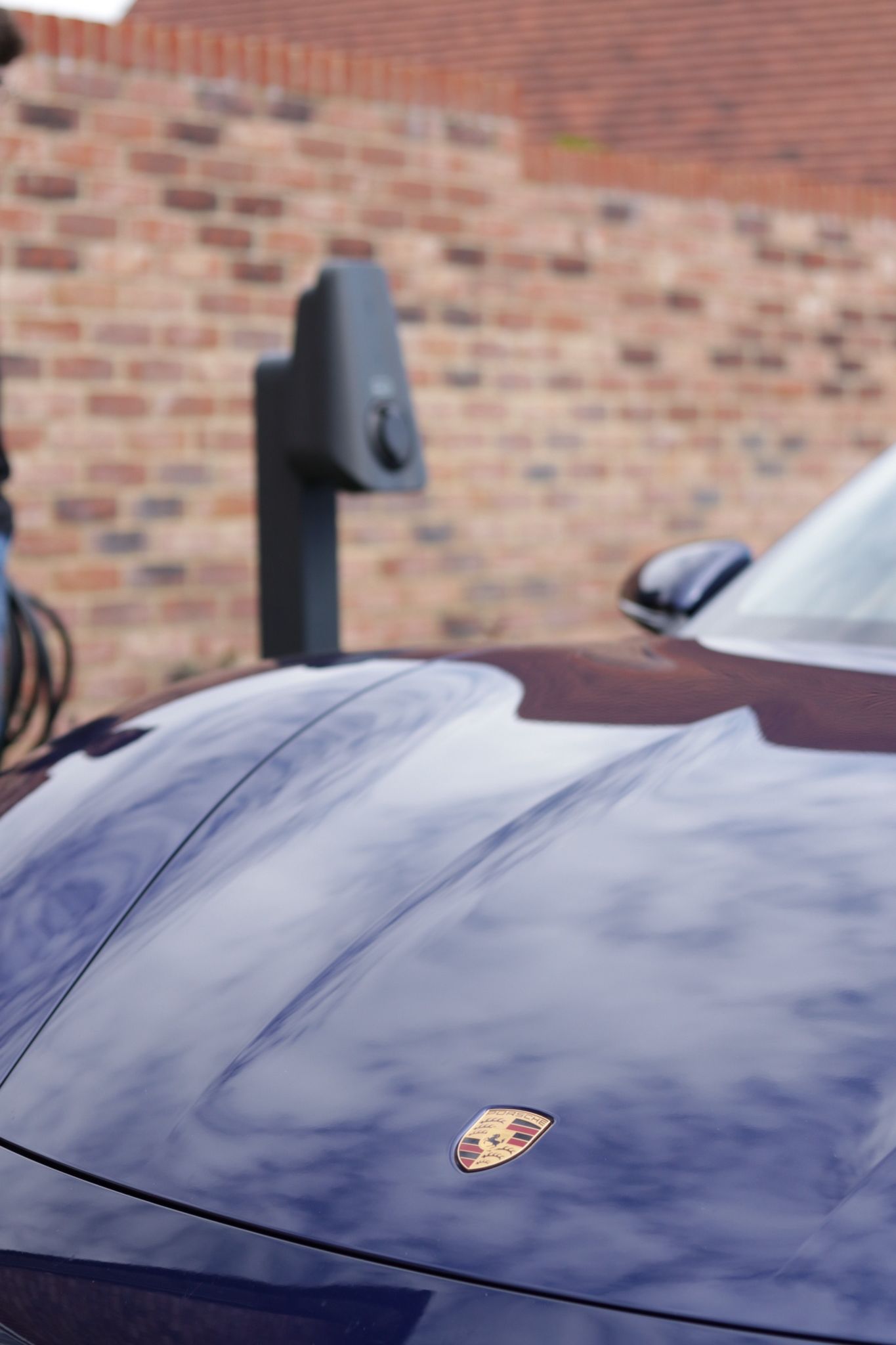 The bonnet of a dark car parked beside a Brim charger