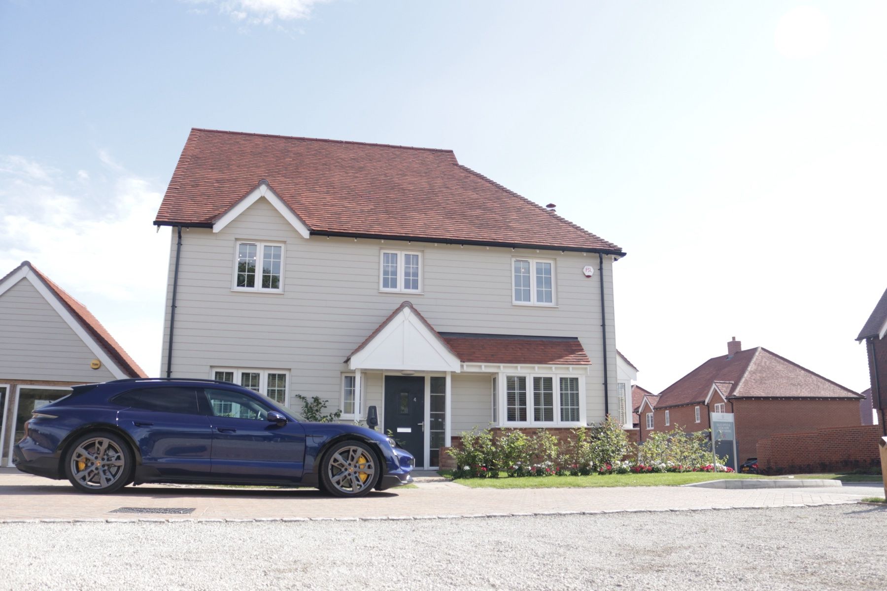 A new-build home with an electric car parked on the drive beside its Brim charger