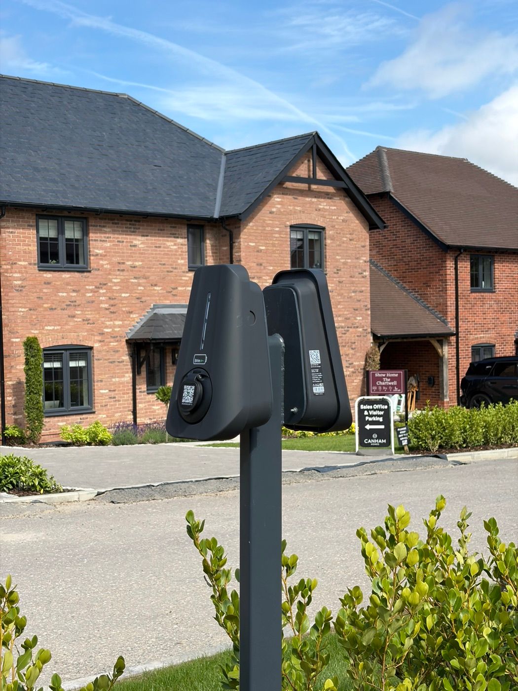 Two Brim chargers on a post in front of new-build homes