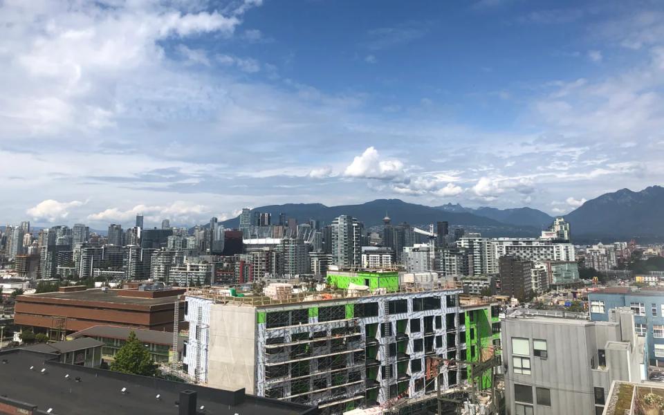 Vancouver buildings and construction cranes beneath a blue sky.