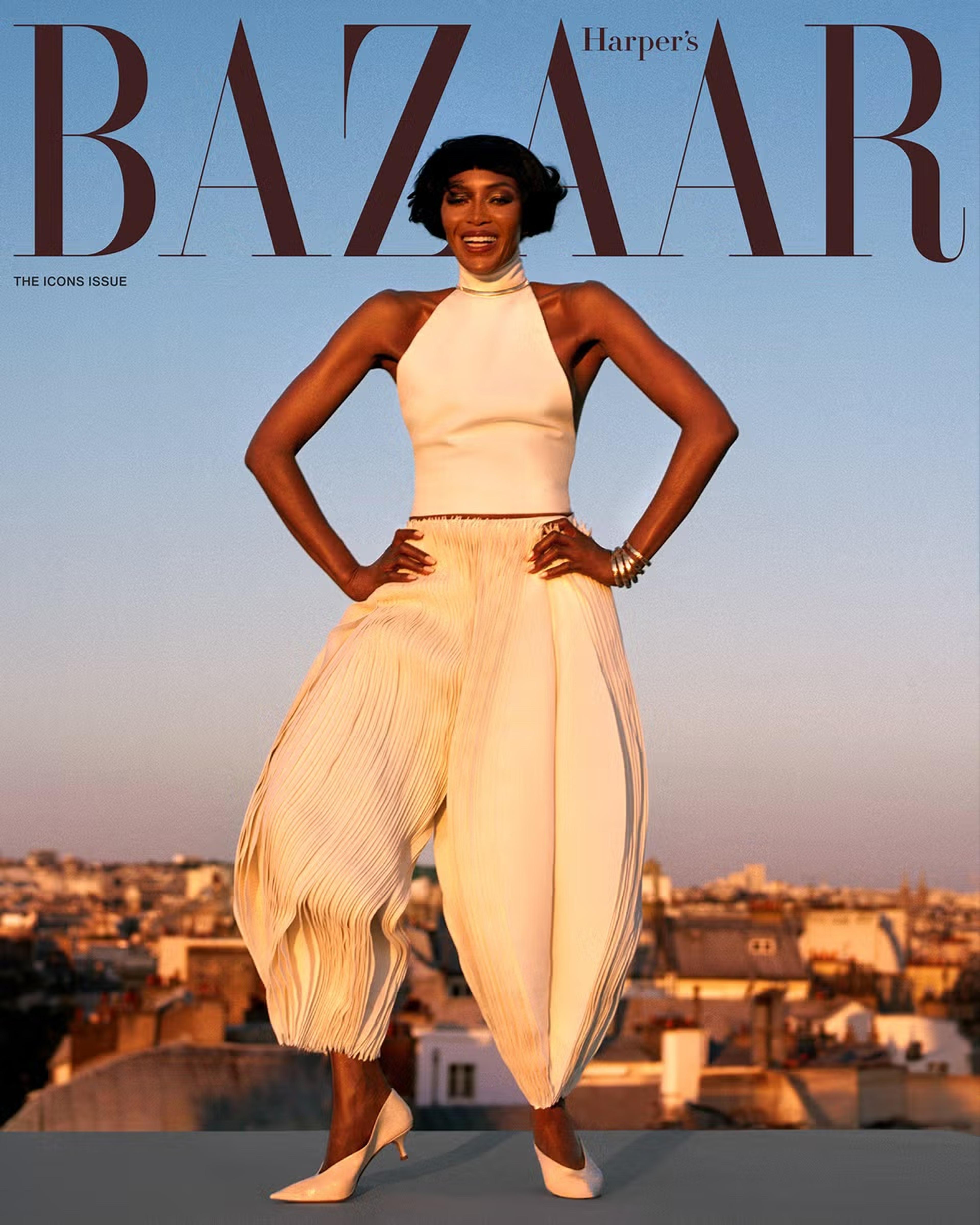 Image of Naomi Campbell in golden cream two piece shirt and pant set with matching heels.