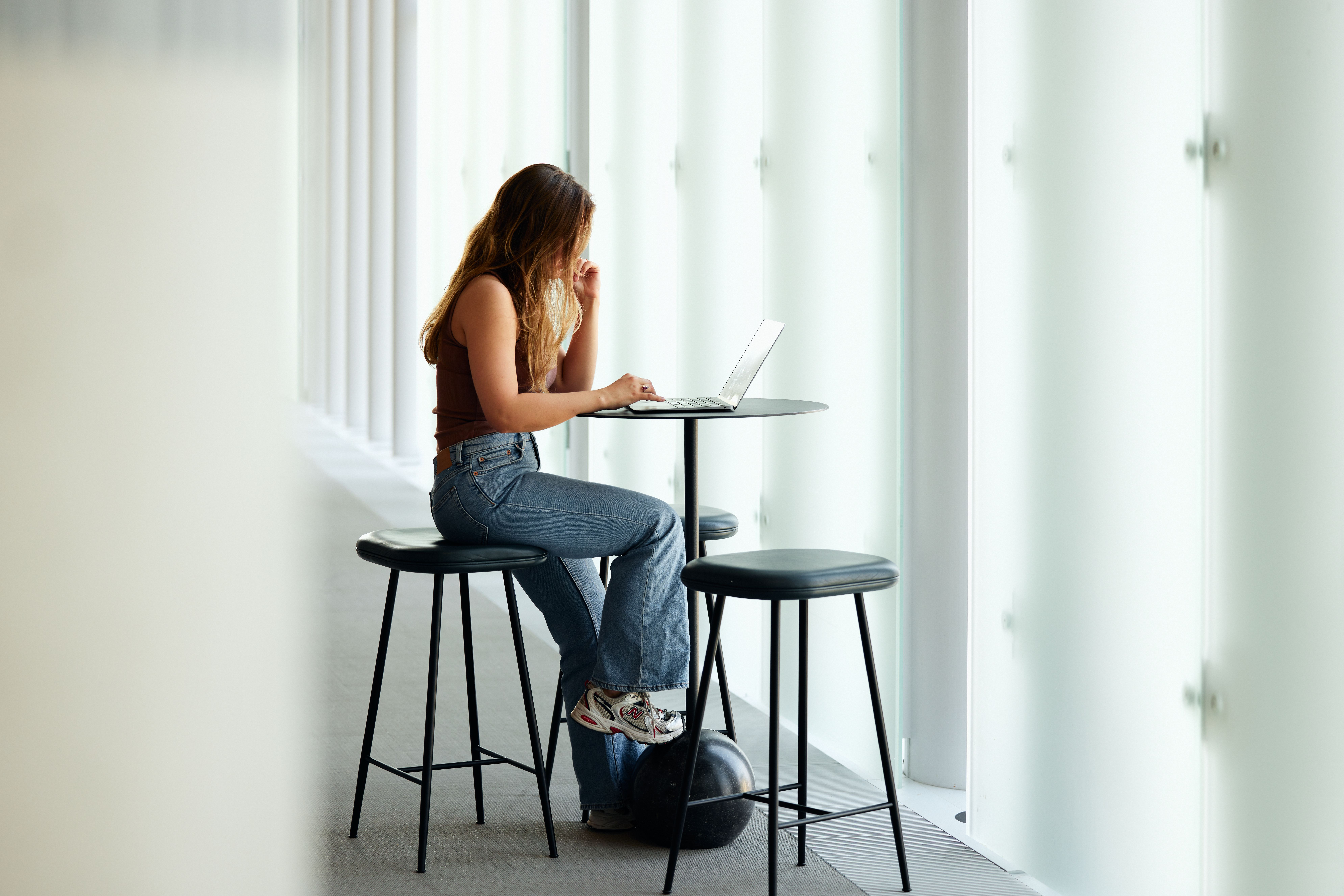 en kvinne sitter ved et bord og bruker en bærbar datamaskin.