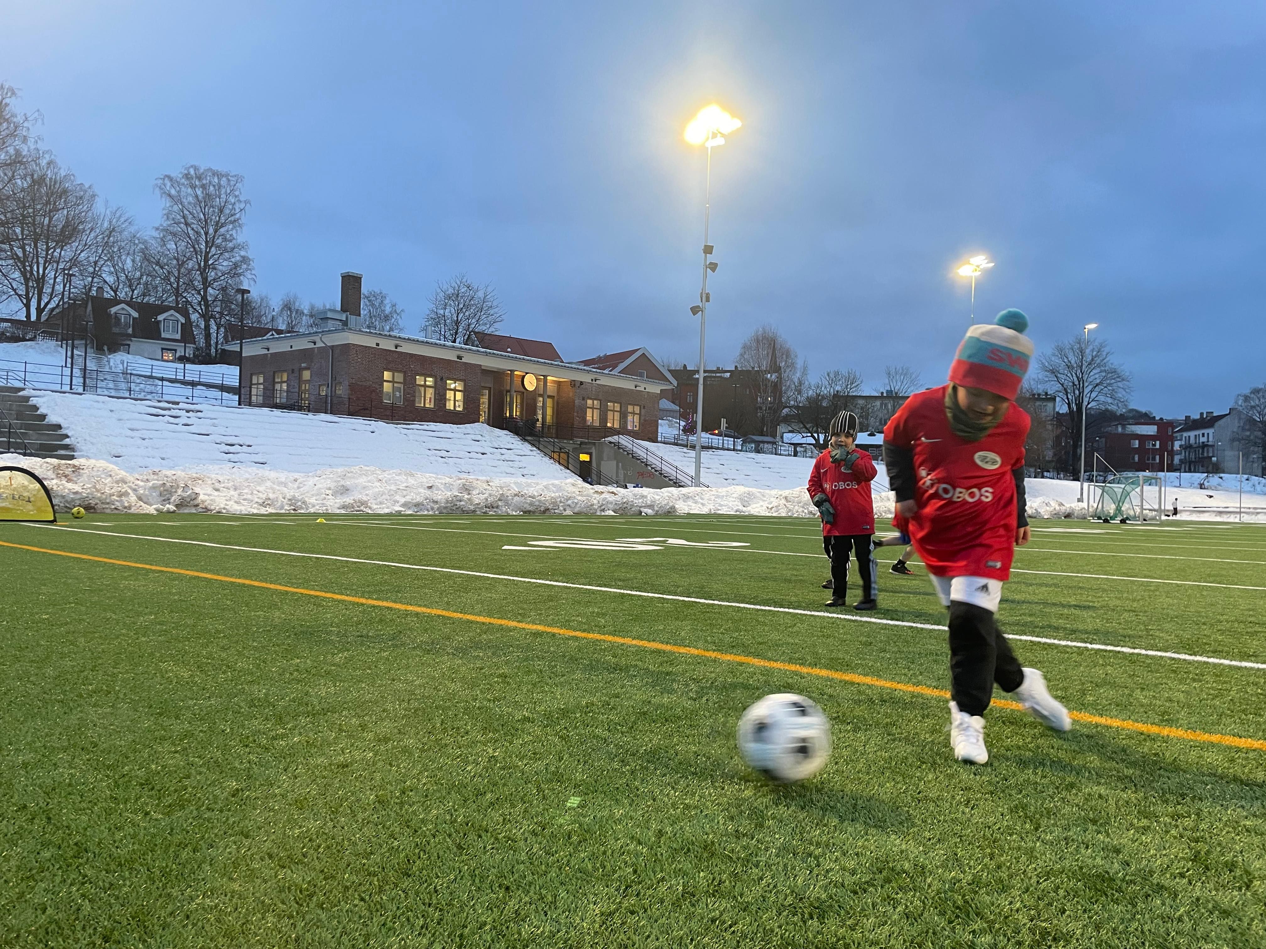 Gutter spiller fotball på gressbane.
