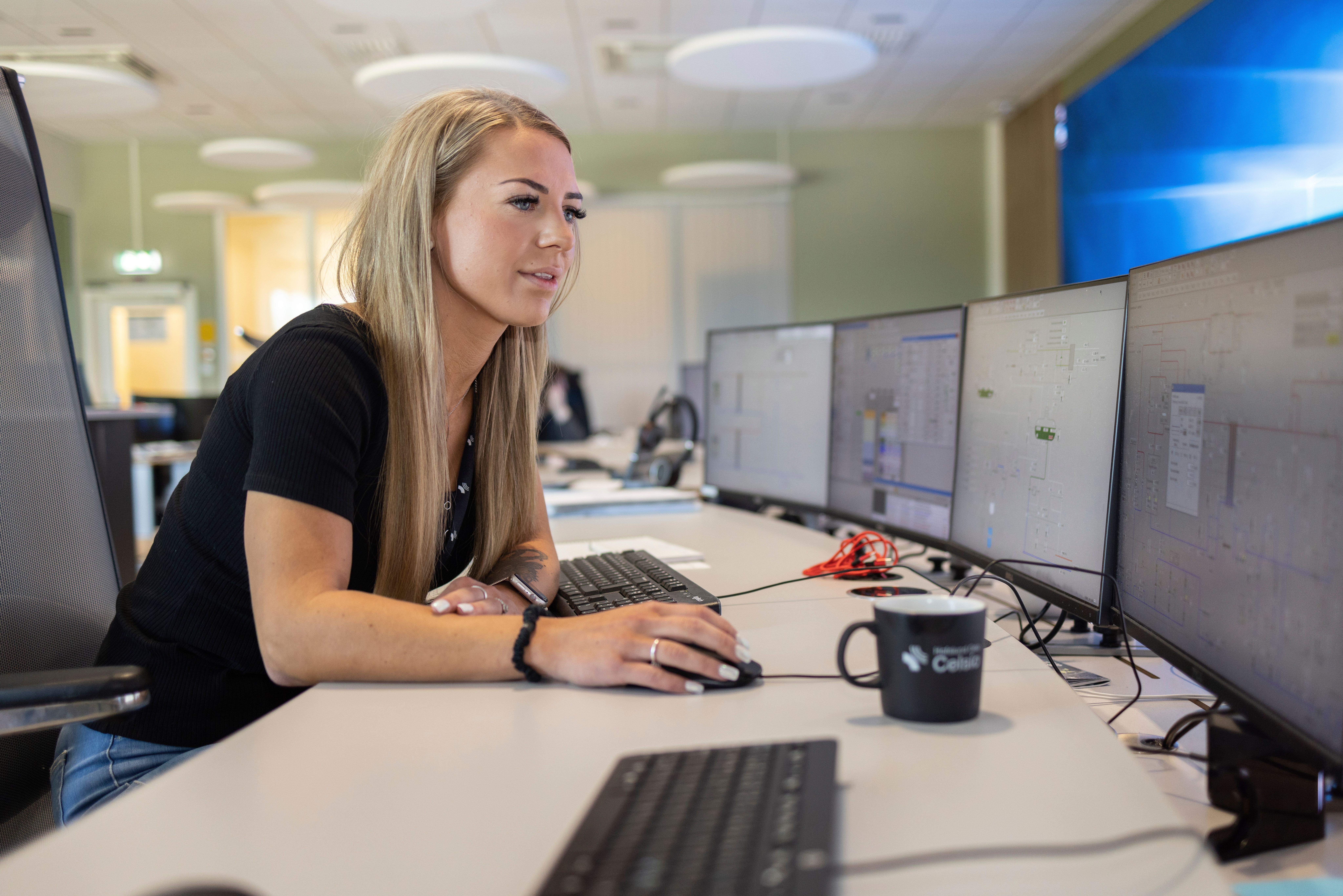 Kvinne ved skrivebord ser inn i dataskjerm