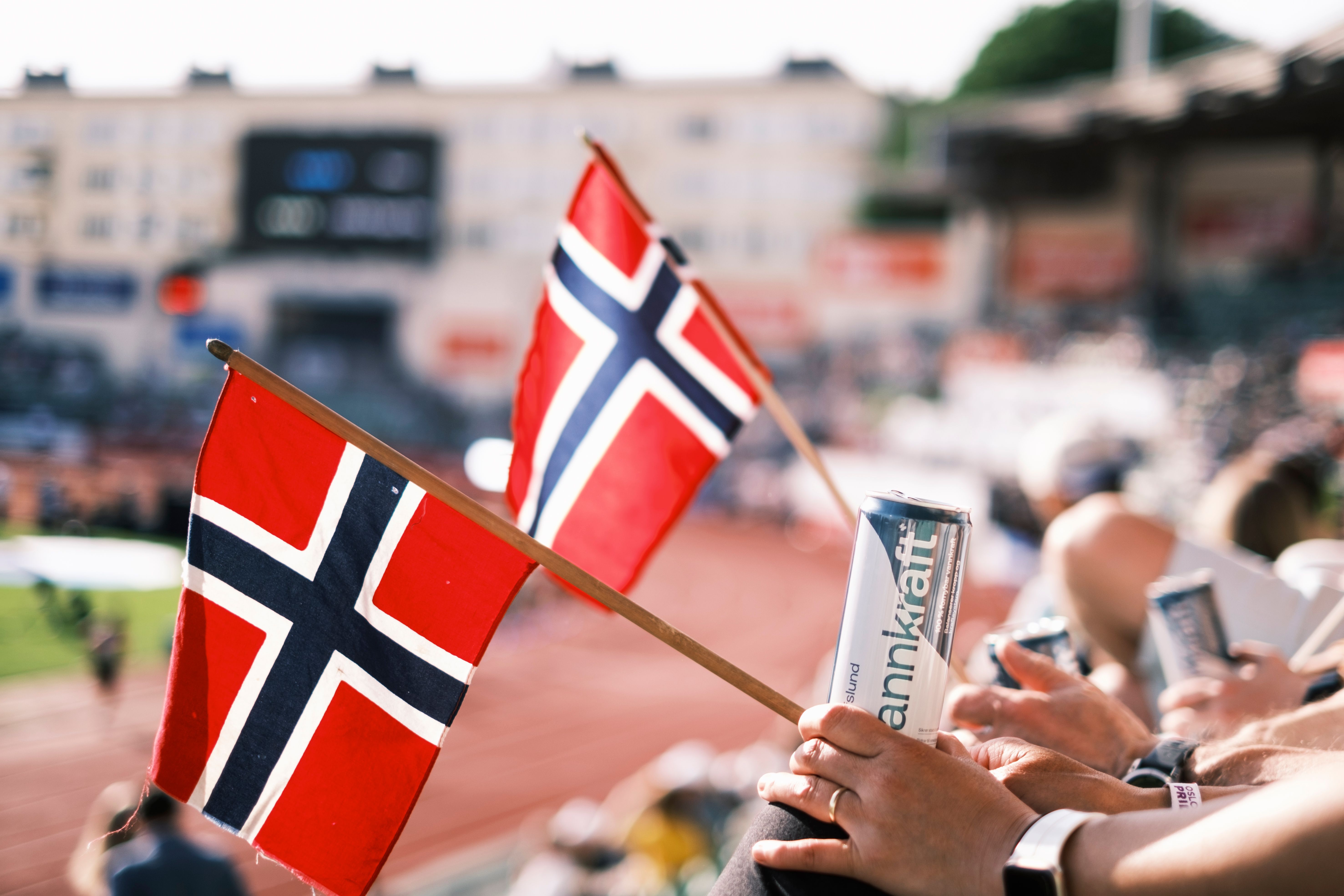 Flagg og hender med boks med drikke, på Bislett stadion
