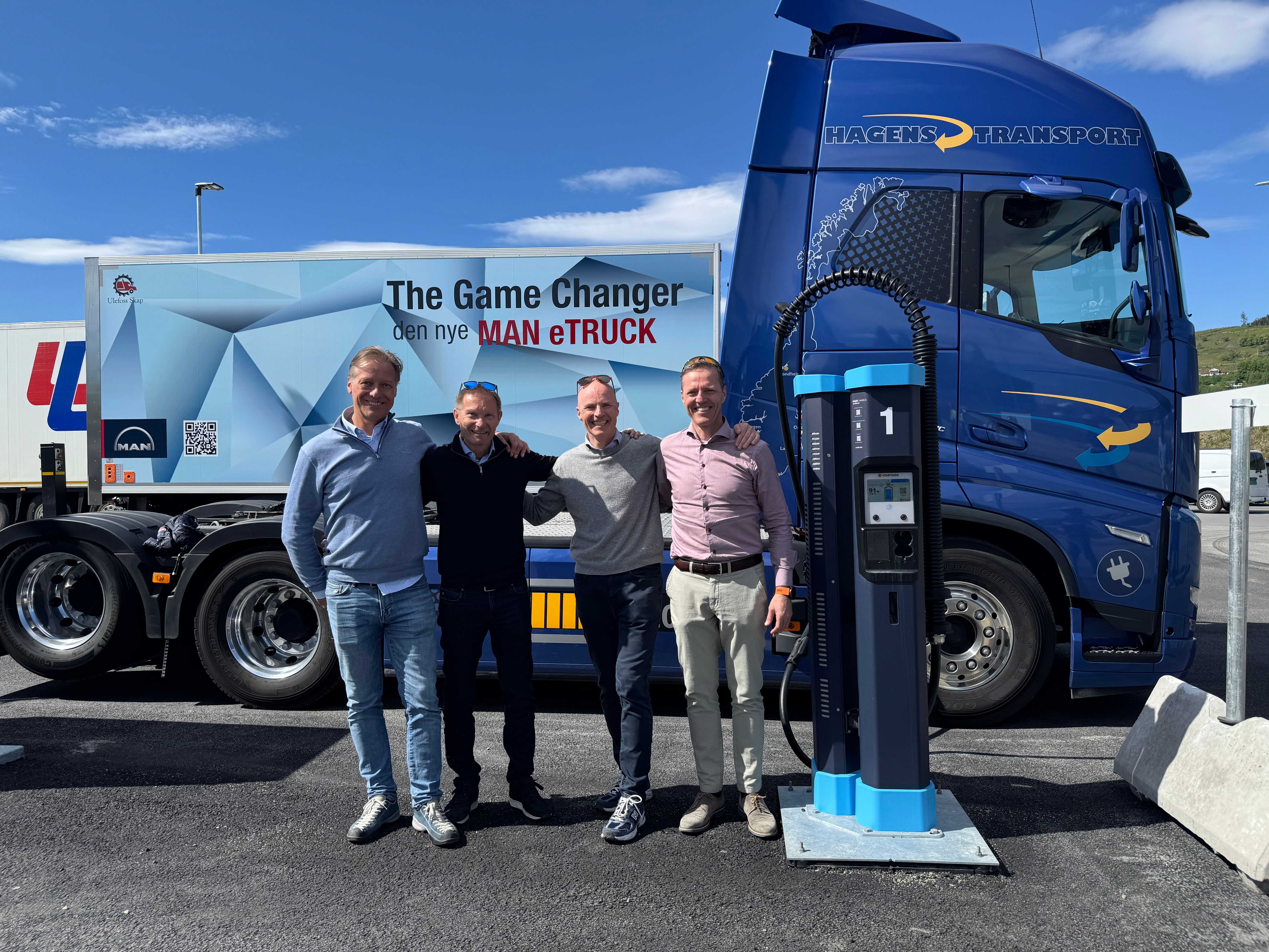 En gruppe menn står foran en elektrisk lastebil og en lader. 