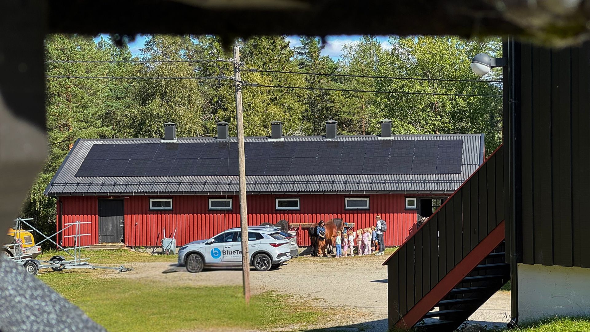 En rød låve i marka, med solcellepanel på taket.