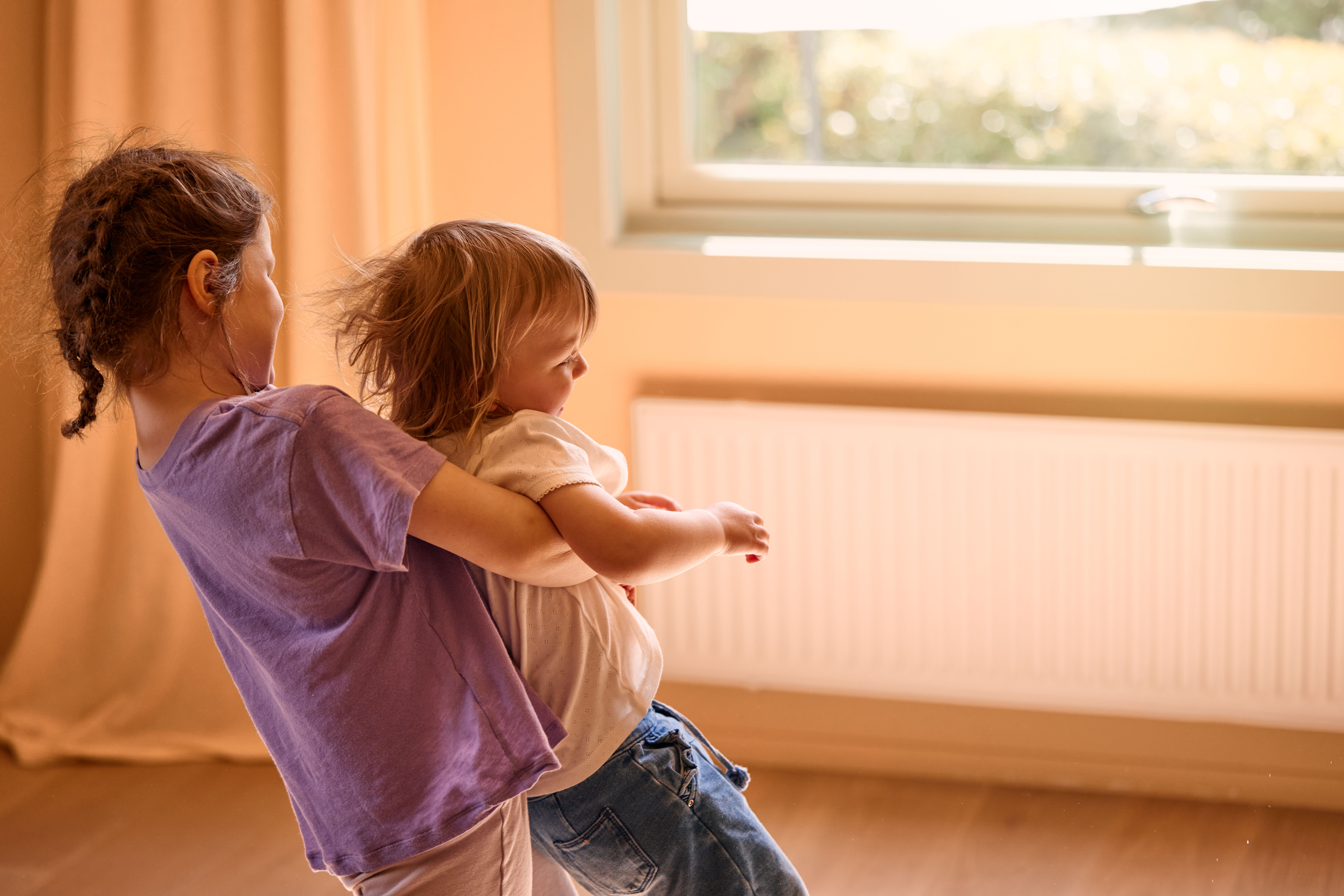 To barn leker i en stue som varmes opp med fjernvarme.