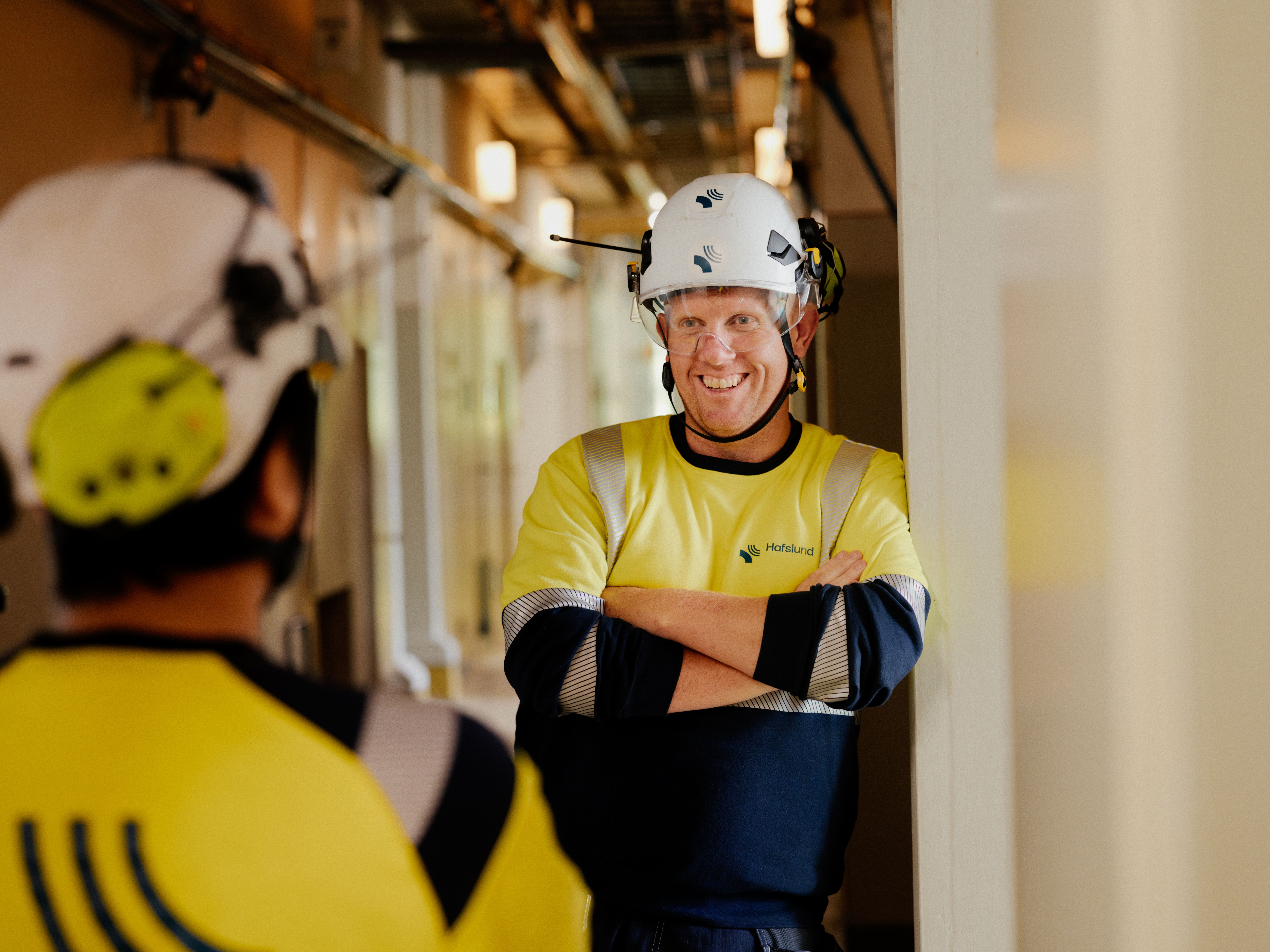To menn i vernetøy står og prater og ler. 