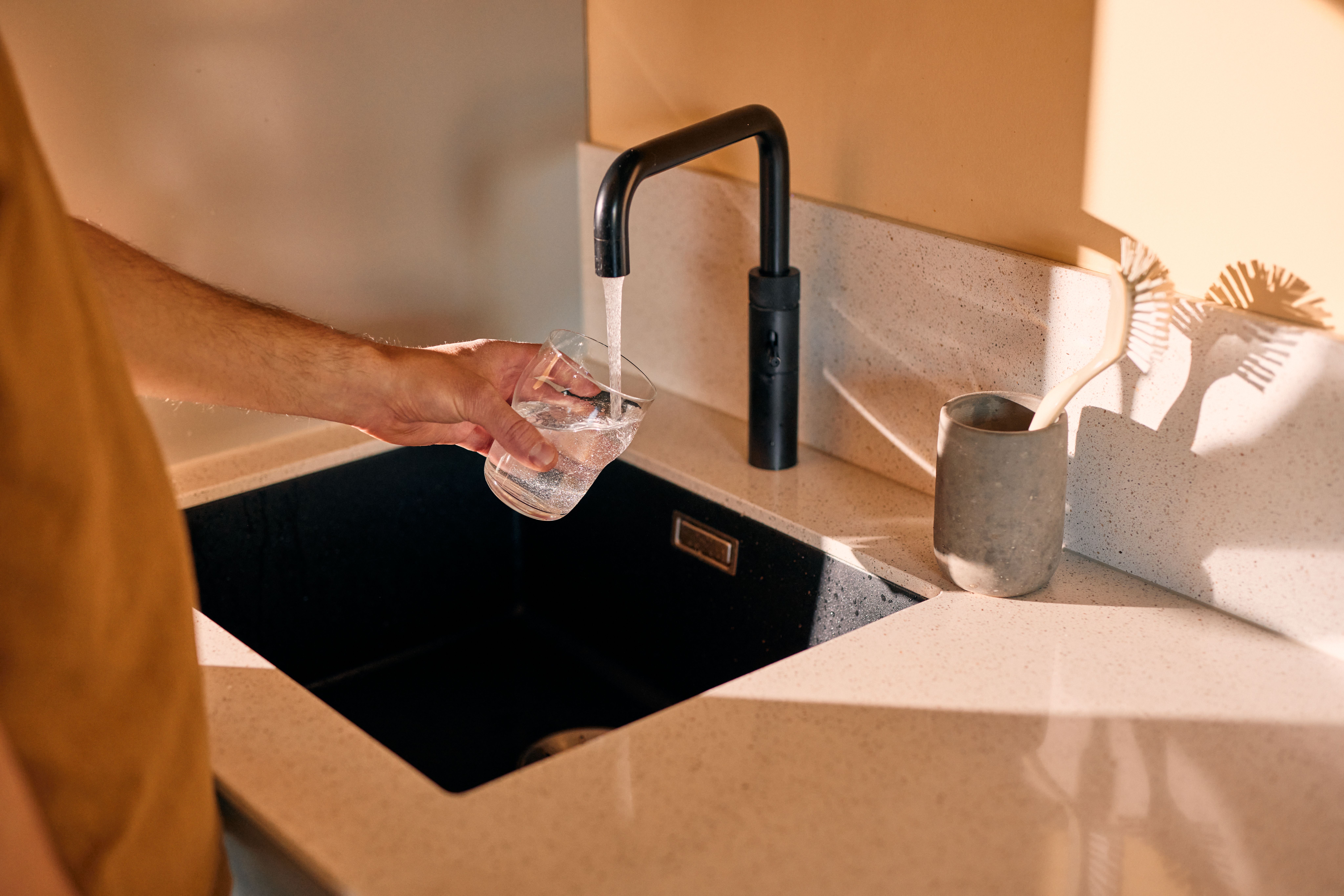 En person fyller et glass med vann fra springen.