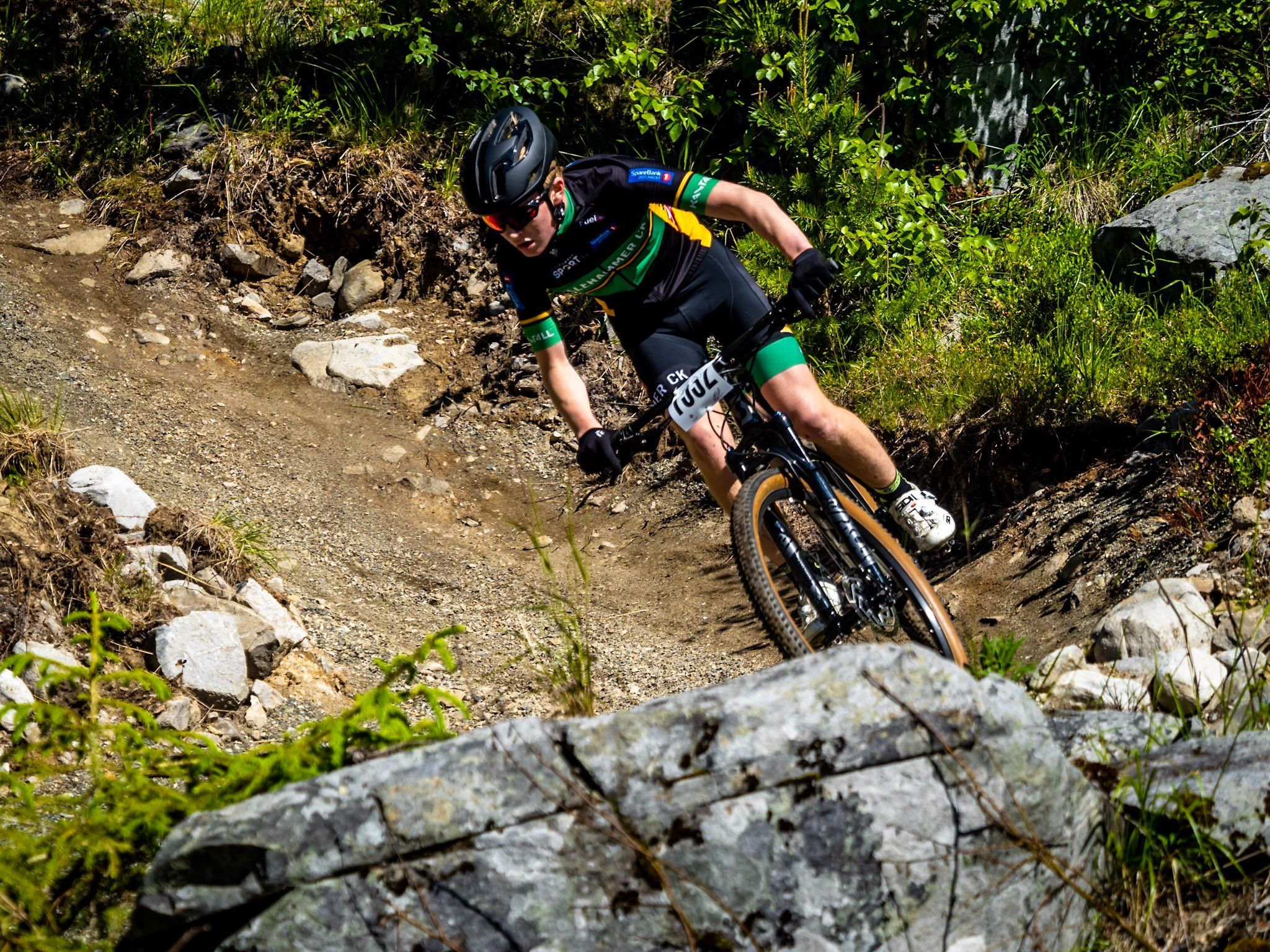 En person som sykler nedover en sti i skogen. 