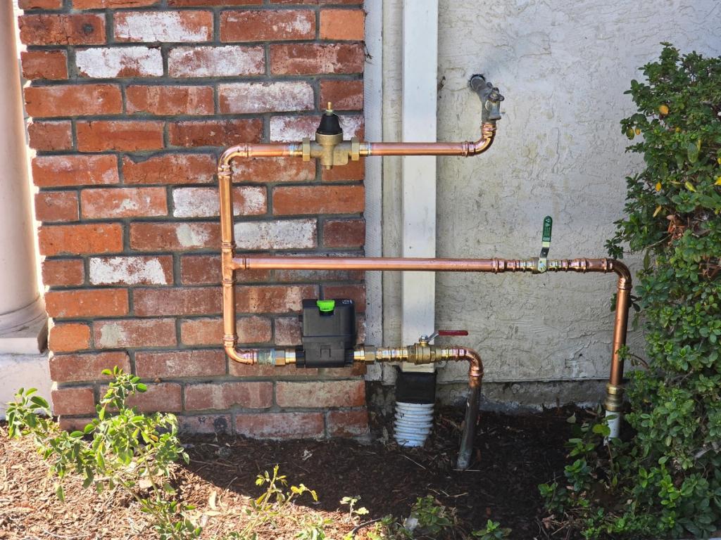 Copper water lines and pressure regulator neatly installed on a brick wall by Chase Rooter & Plumbing.