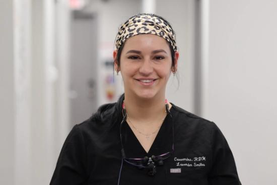 a female dentist wearing a leopard print headband and glasses is smiling for the camera .