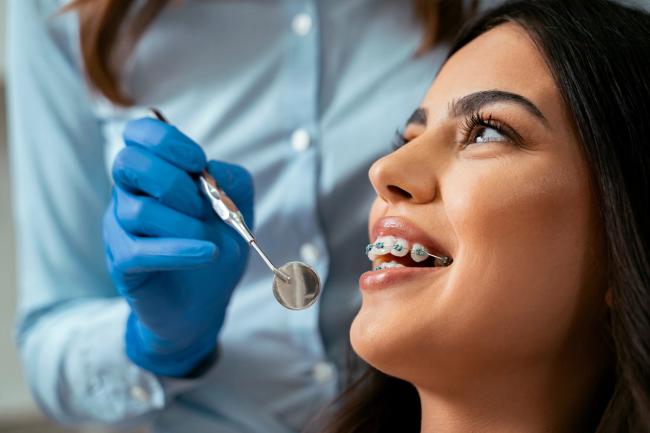 a woman with braces is getting her teeth examined by a dentist .