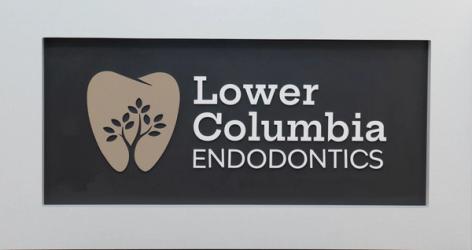 Sign for Lower Columbia Endodontics, featuring a tooth logo with a tree silhouette.
