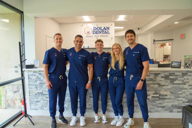 a group of dentists are posing for a picture in a dental office .