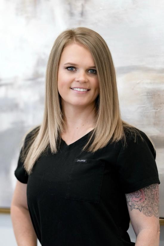 the woman is wearing a black scrub top and has a tattoo on her arm .