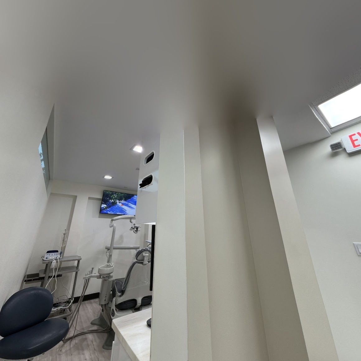a dental office with a dental chair and a television on the wall .