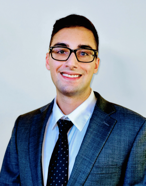 a man wearing glasses and a suit smiles for the camera