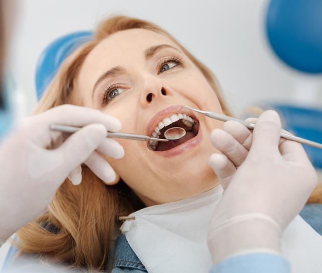 a woman is having her teeth examined by a dentist .